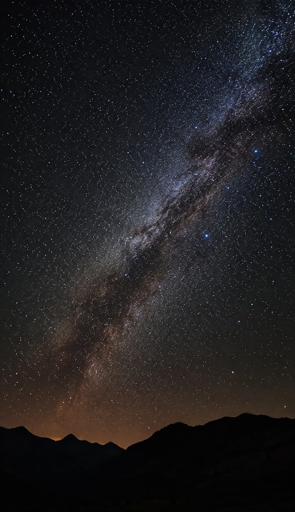 solo traveler stargazing under the Milky Way on a dark mountain ridge
