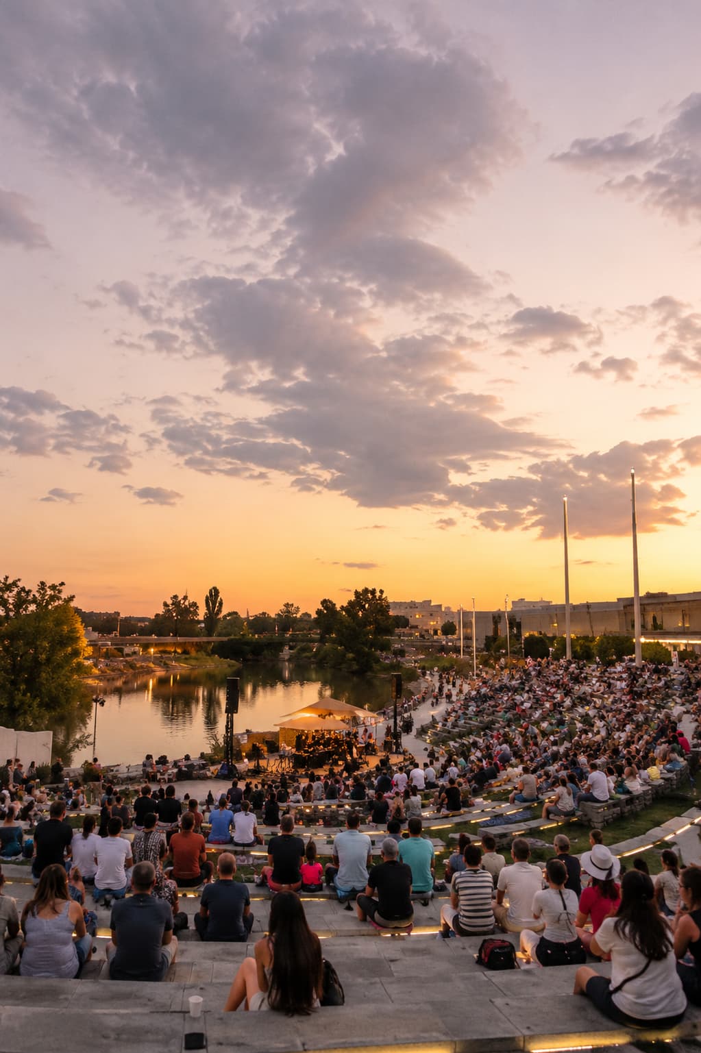 open-air concert at sunset beside a river — attending a local festival alone