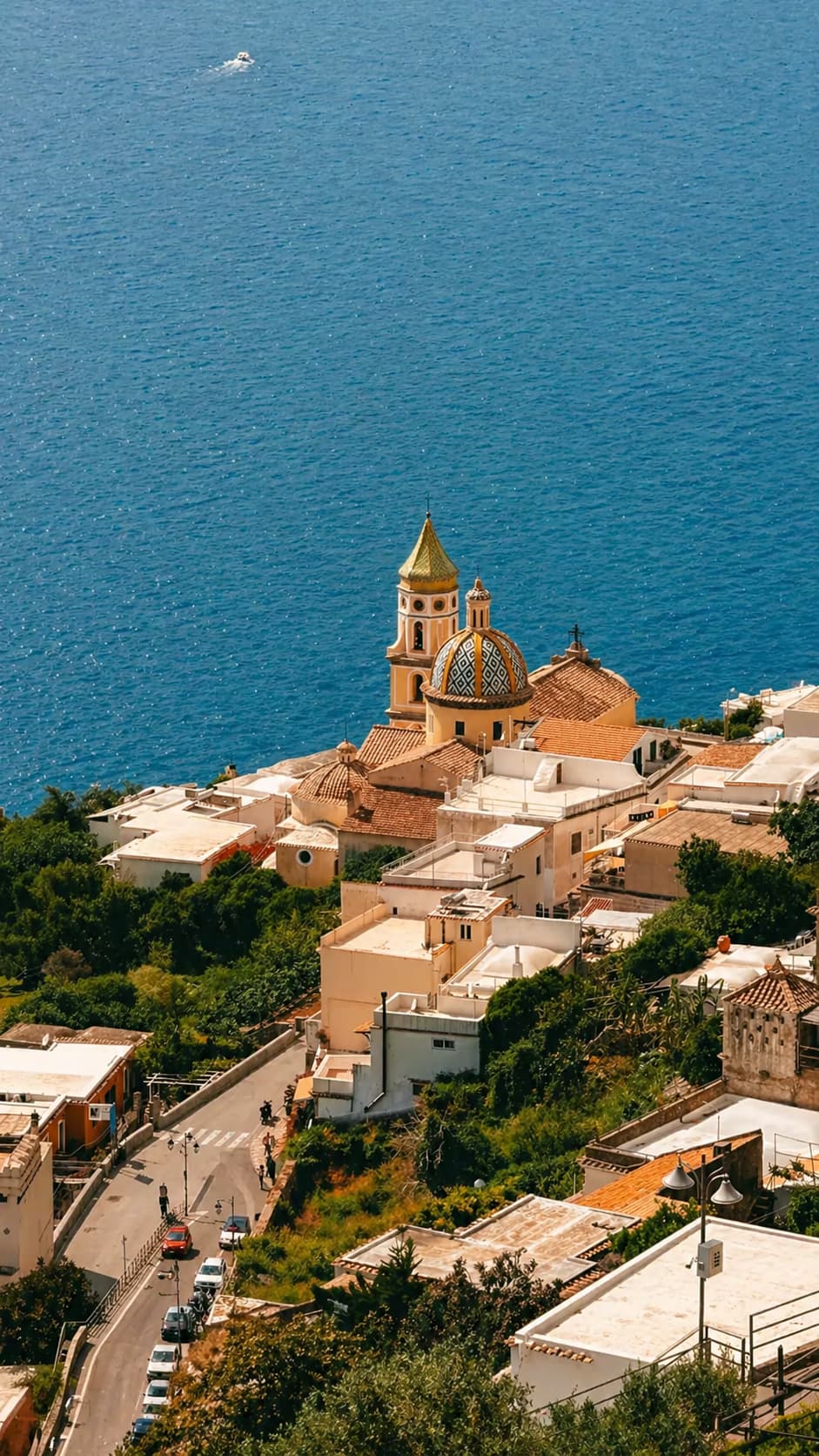 Aerial view of Praiano on the Amalfi Coast with church dome and deep blue sea — a quieter couples getaway on the Italian coast