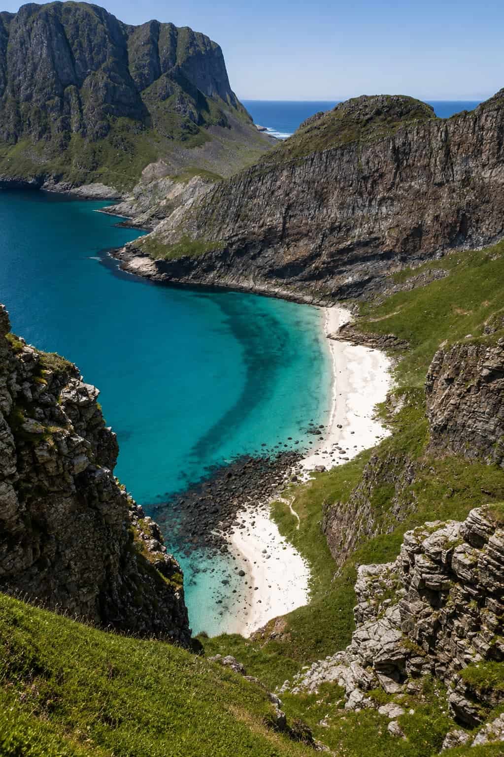 Lofoten Islands Norway — granite peaks rising from Arctic water with red rorbuer cabins on the shoreline at golden hour