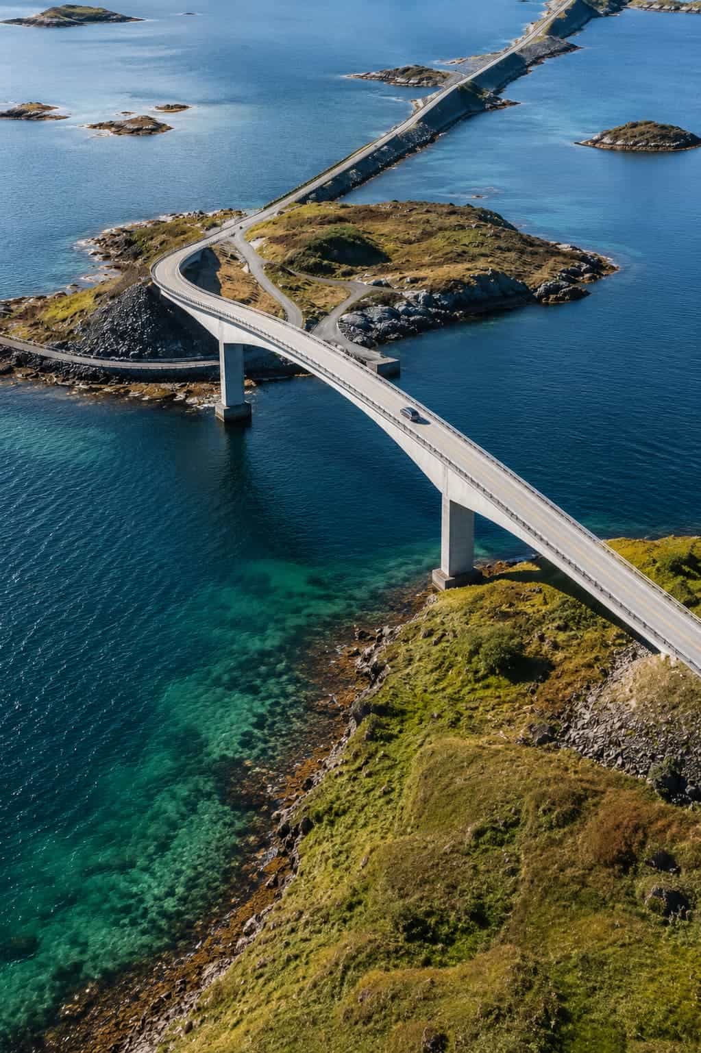 E10 highway Lofoten Islands Norway — road crossing a bridge between islands with mountain peaks reflected in still water either side