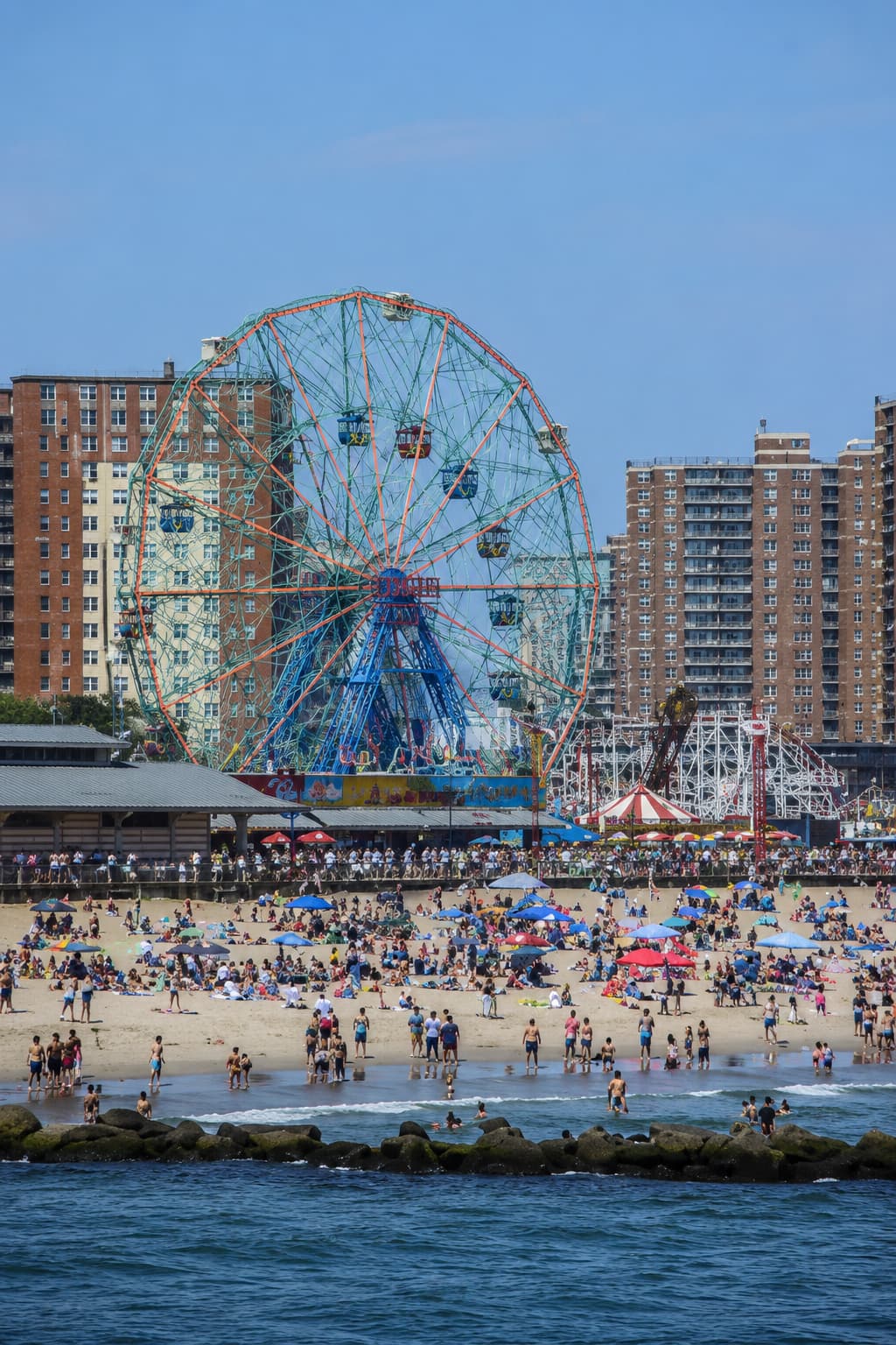Coney Island beach and the Wonder Wheel crowded with people on a summer afternoon in New York