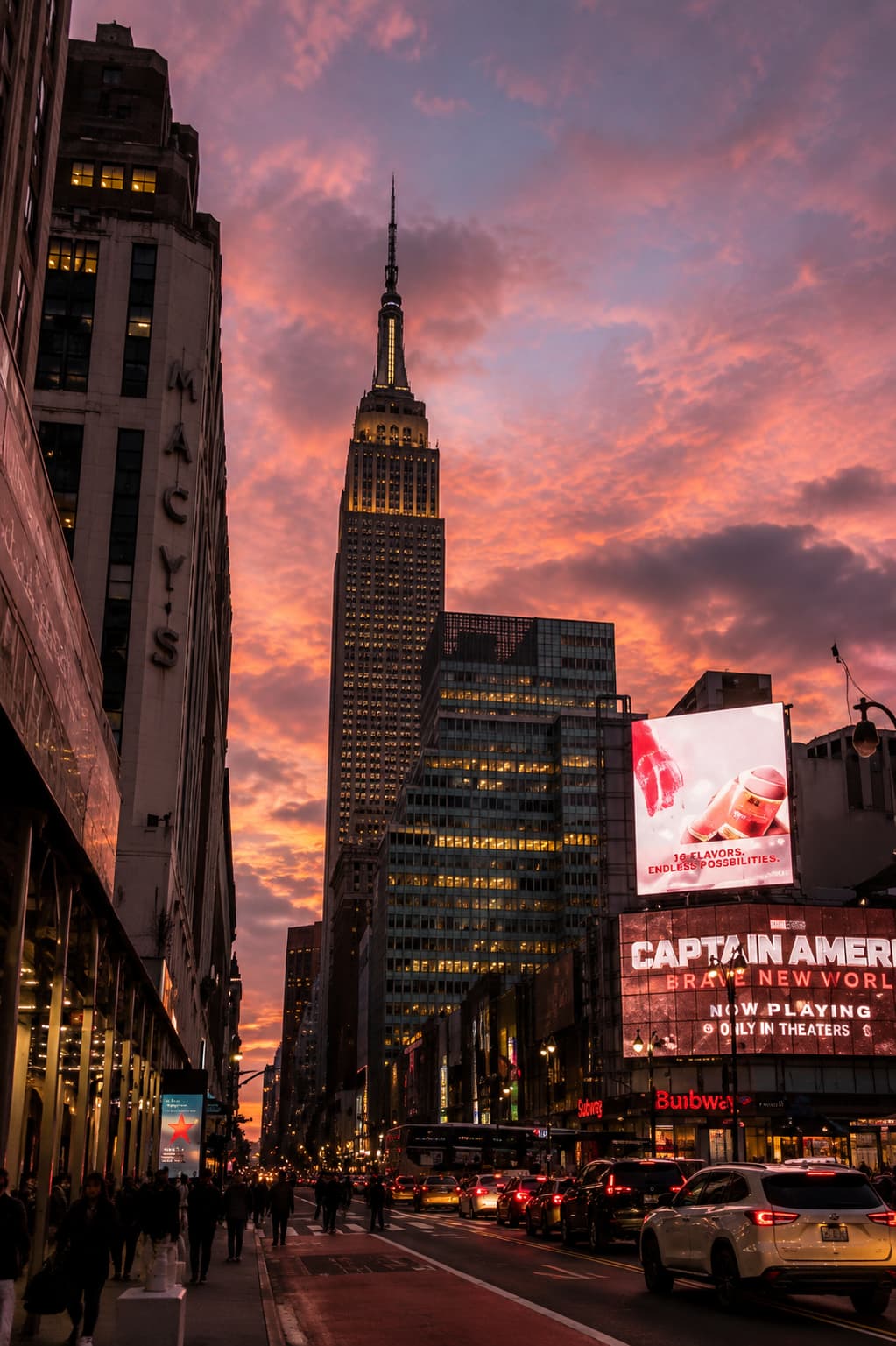 The Empire State Building rising above Midtown at a vivid pink sunset, street level view