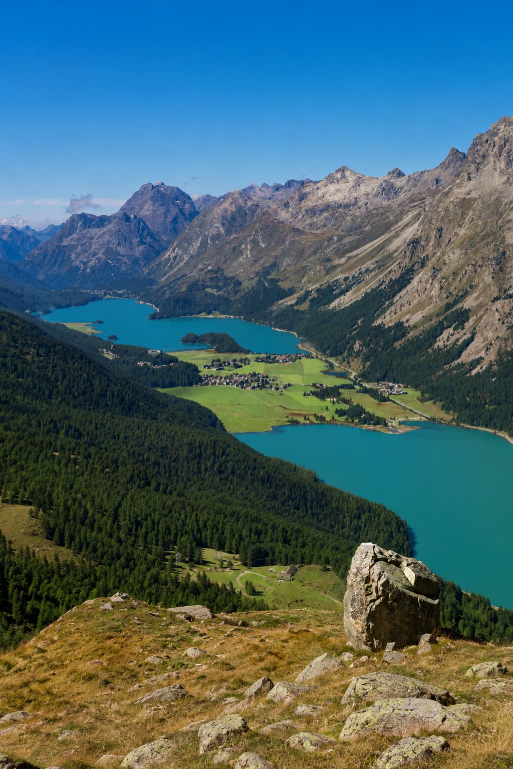 Bright blue glacial lakes of the high Engadin valley near St. Moritz seen from a rocky ridge, Switzerland