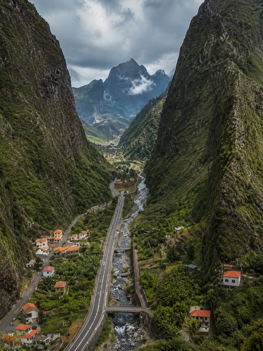 A mountain road winding through a steep green valley in Madeira's interior