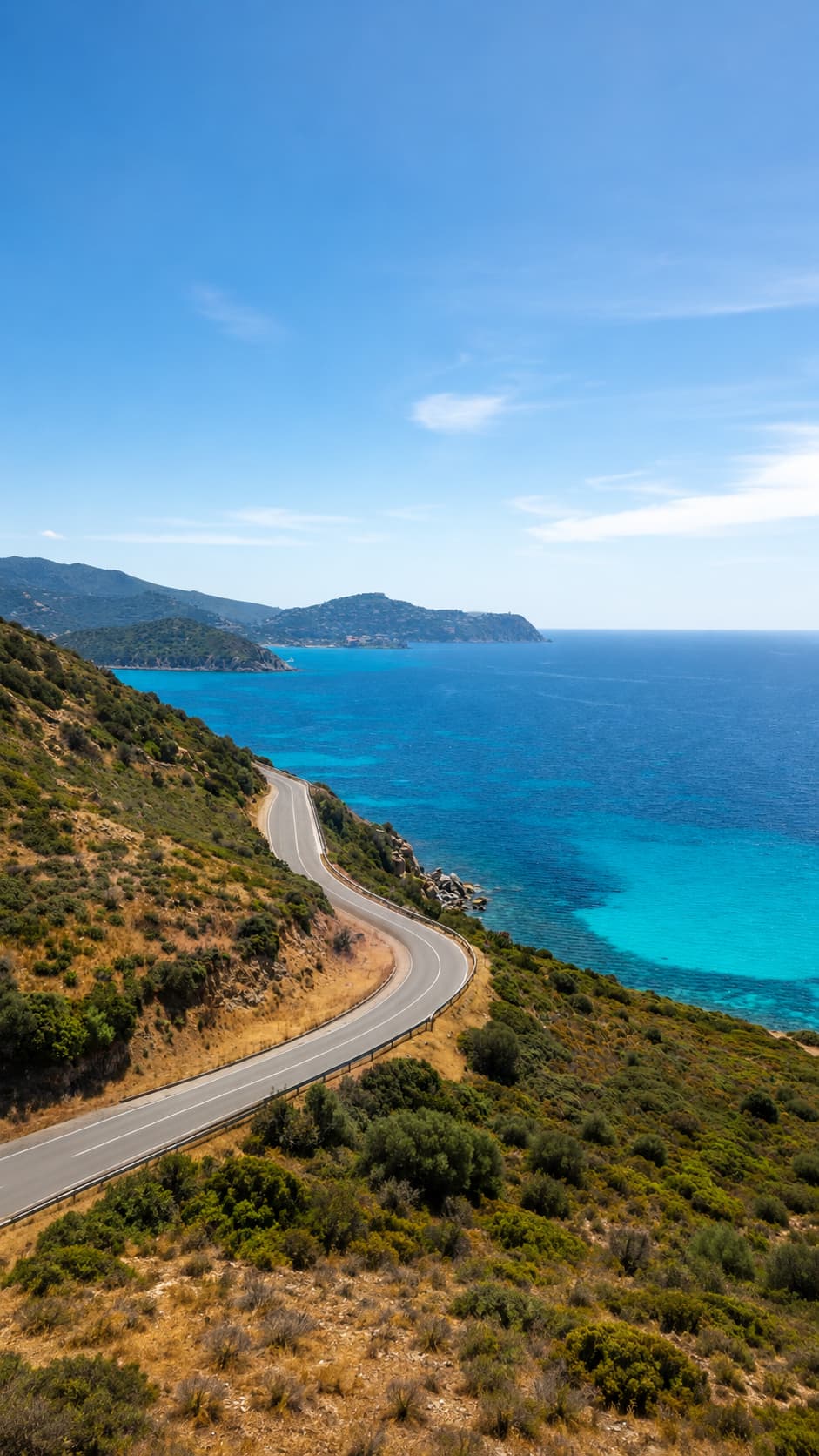 A winding coastal road following the blue sea and scrub-covered hills of the northern Sardinia coastline