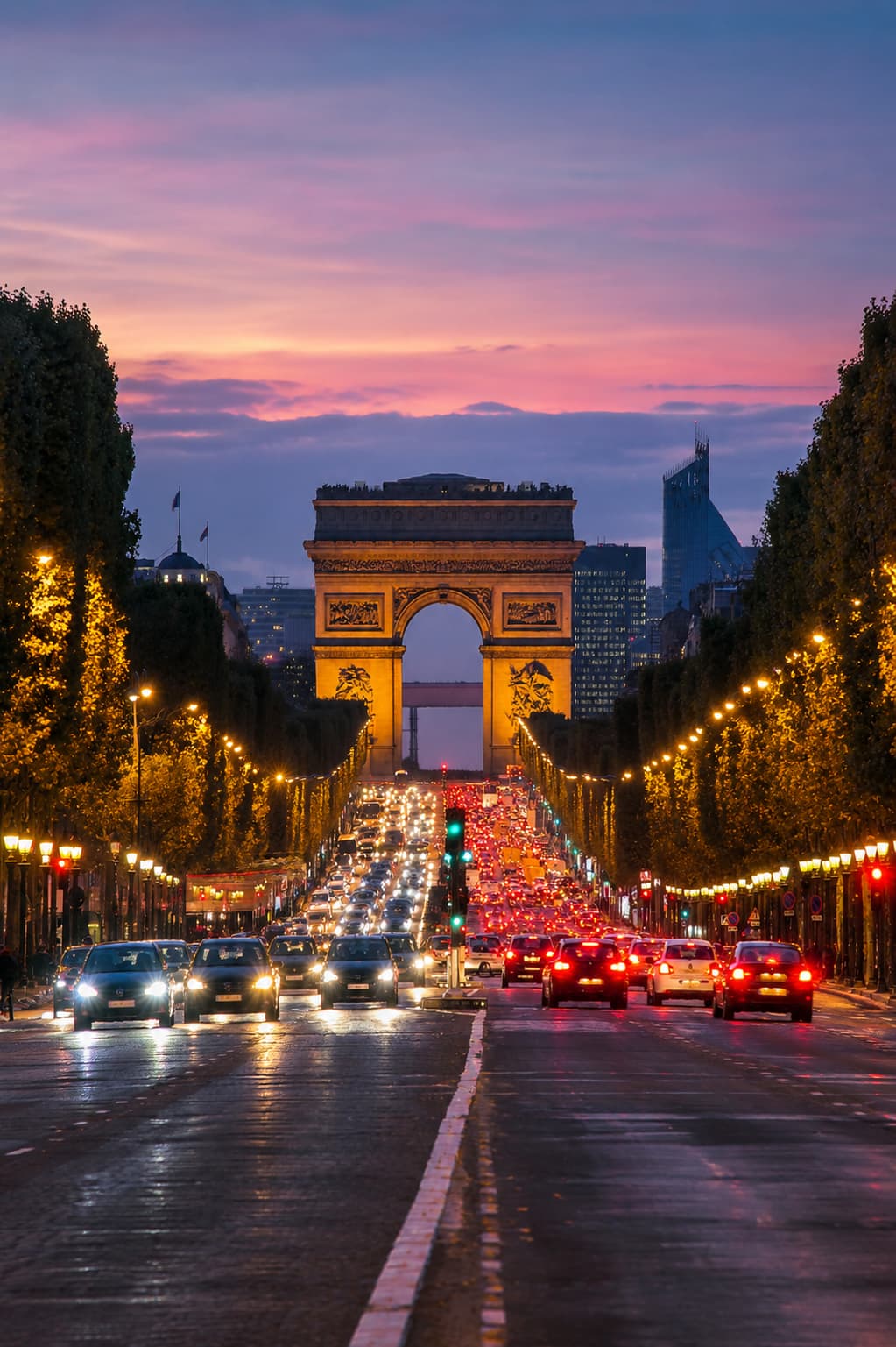 The Arc de Triomphe at dusk, traffic streaming down the Champs-Elysees