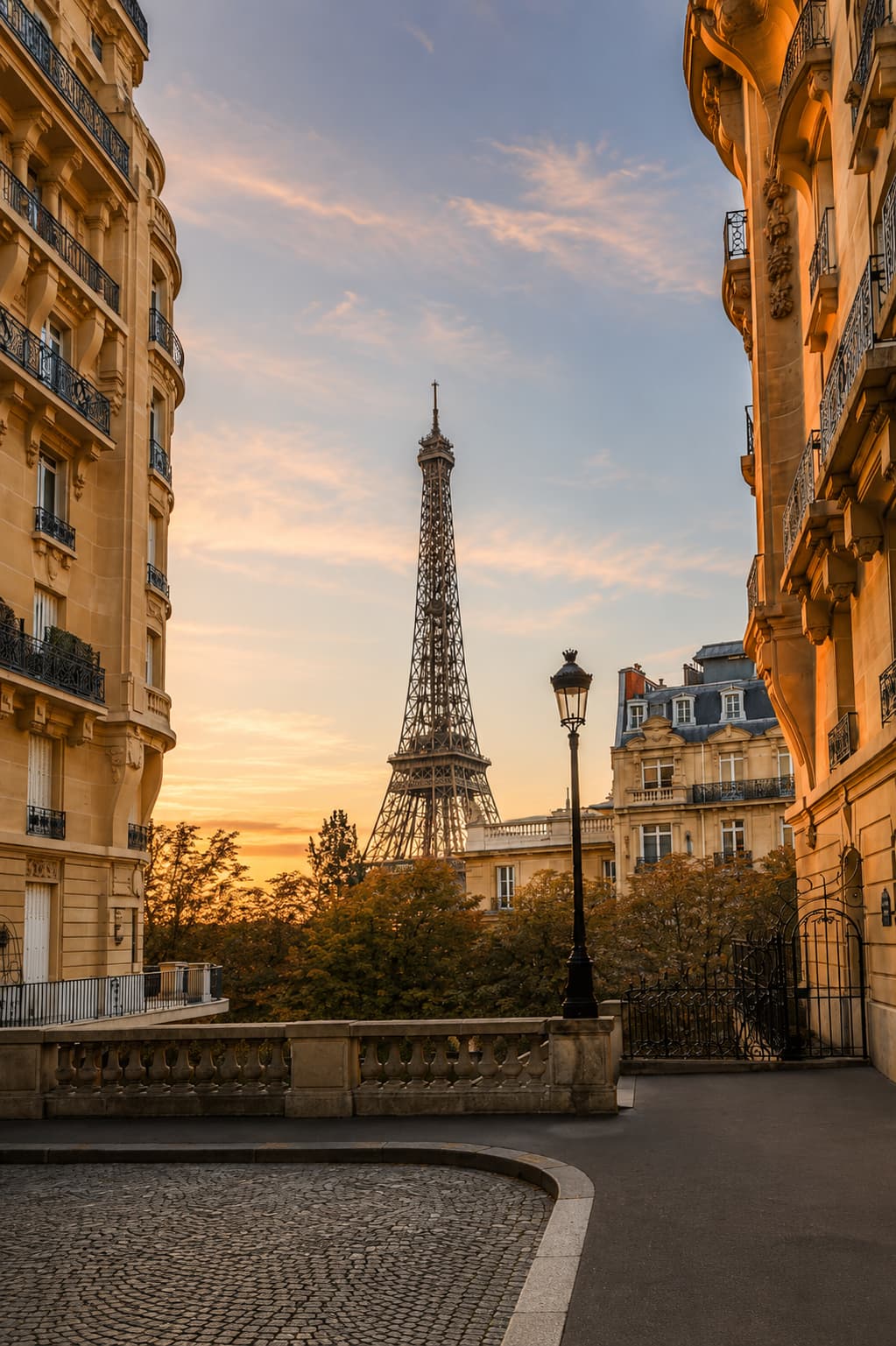 A quiet cobblestone street framing a golden-hour view of the Eiffel Tower