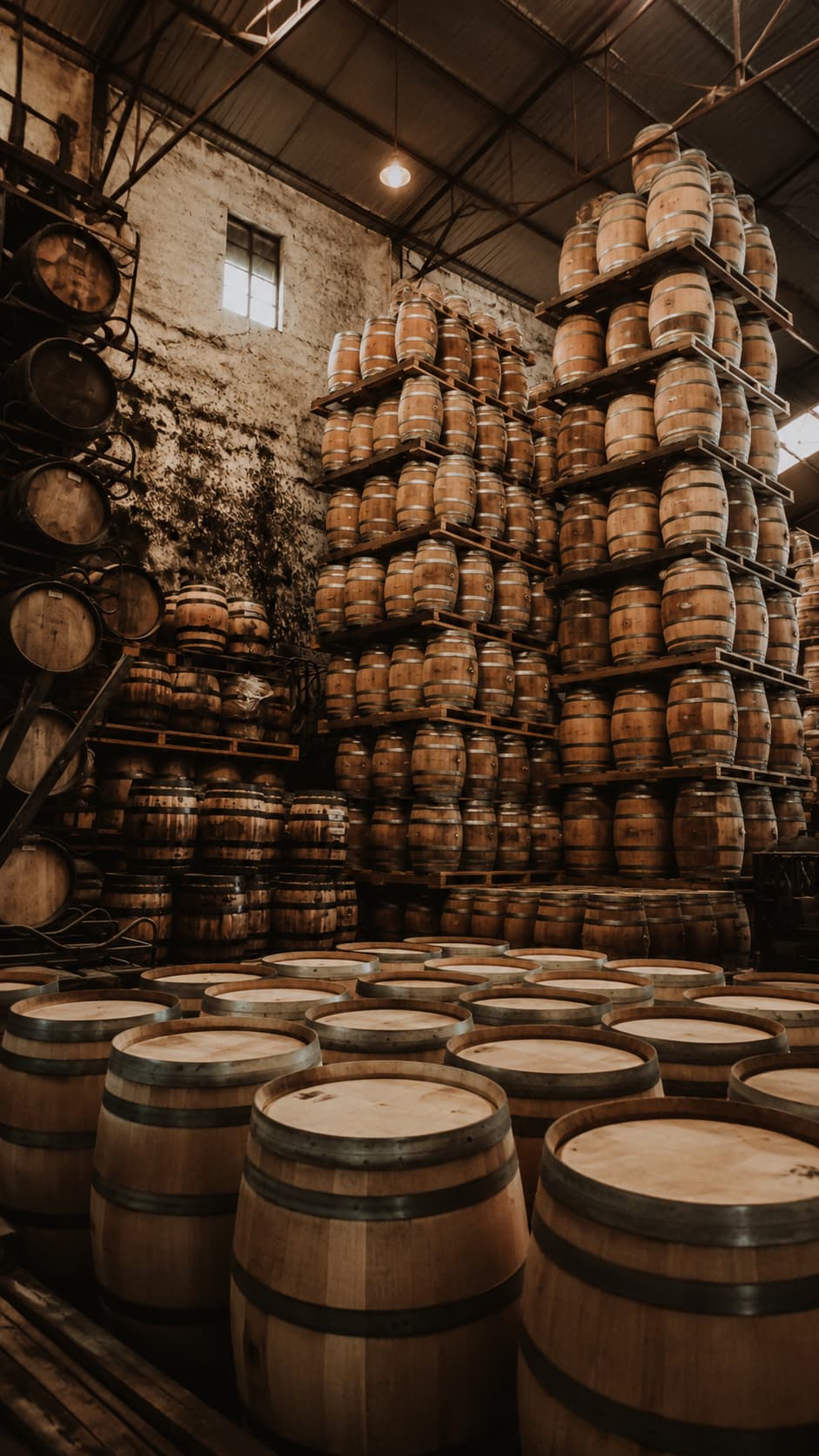 Stacked oak port wine barrels ageing inside a Vila Nova de Gaia cellar on a Porto itinerary