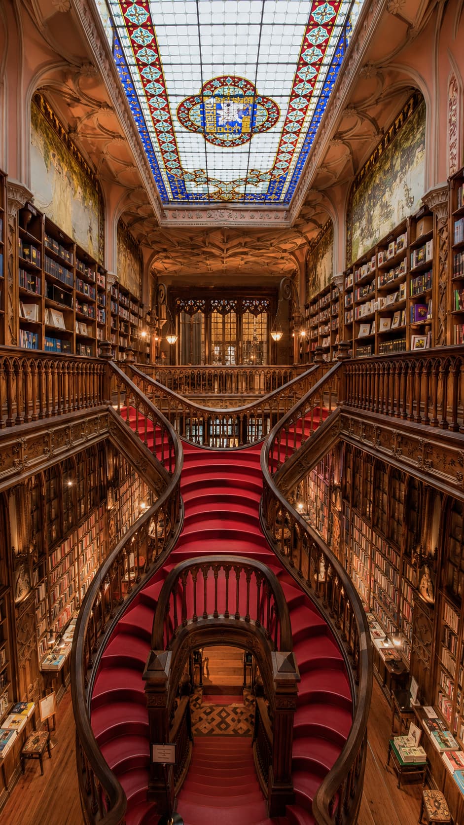 The curved red staircase and stained-glass ceiling inside Livraria Lello bookshop in Porto