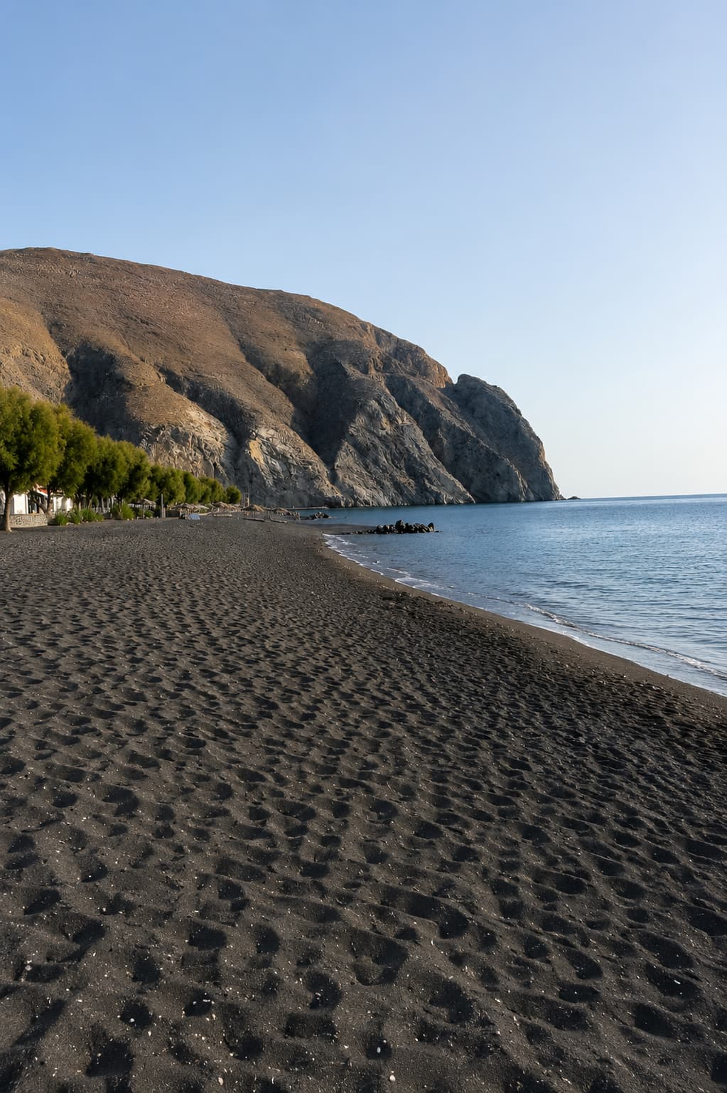 Santorini's volcanic black-sand beach at Perissa, the coarse shoreline Mykonos doesn't have