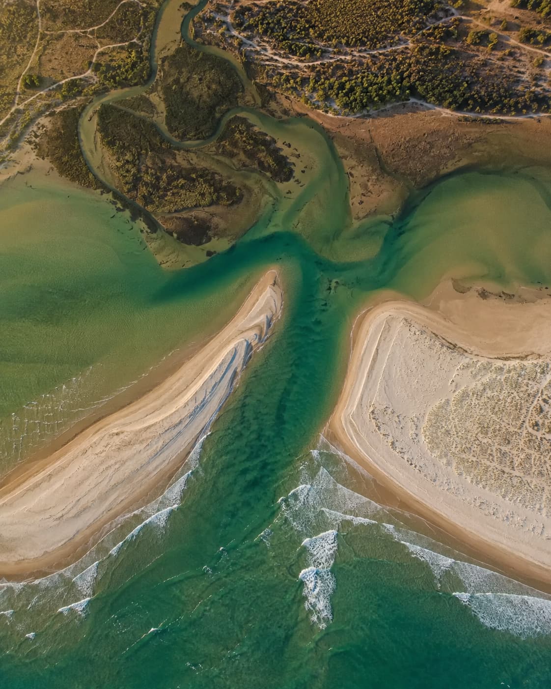 Aerial drone view of the Ria Formosa lagoon system in the eastern Algarve, showing tidal channels, sandbanks, and shallow green water meeting the Atlantic Ocean