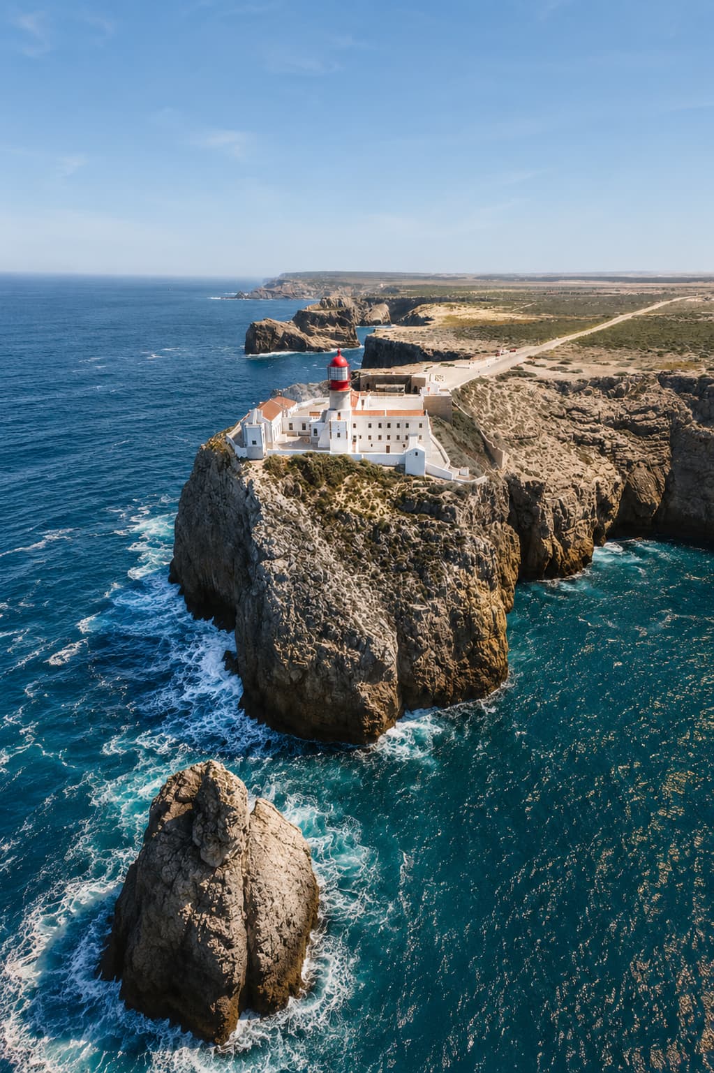 Aerial view of Cabo de São Vicente lighthouse at the southwestern tip of the Algarve, Portugal, perched on dramatic sea cliffs above crashing Atlantic waves