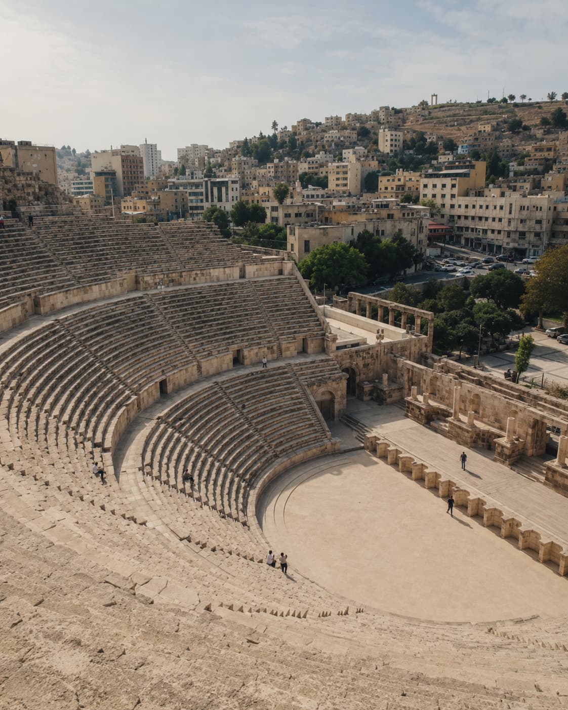 The steep stone seating of the 2nd-century Roman Theatre in downtown Amman, with the pale city rising on the hillside behind it