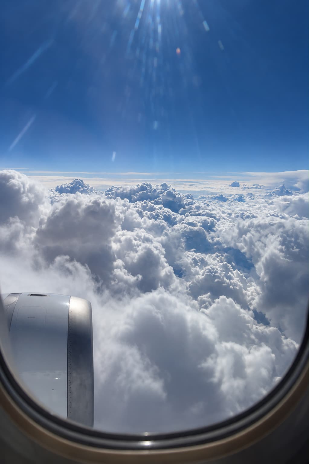The view from an aircraft window over a bright bank of clouds and blue sky, suggesting a long-haul escape beyond Europe in August