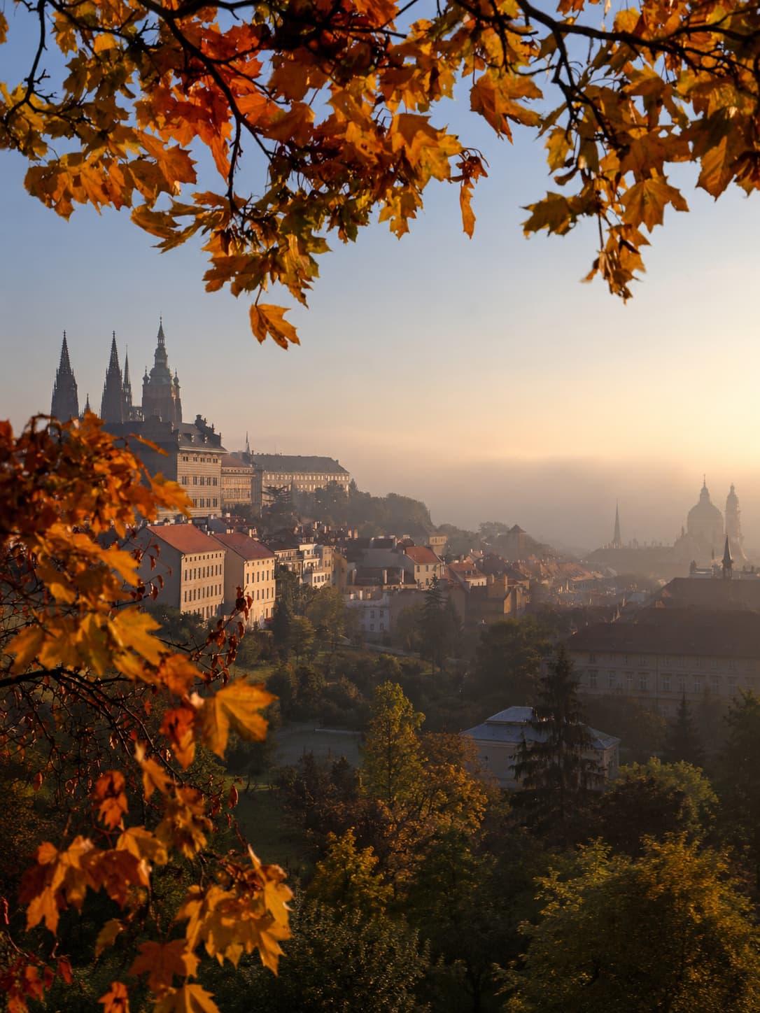 Prague Castle and Gothic spires framed by autumn leaves in October, best European cities in October