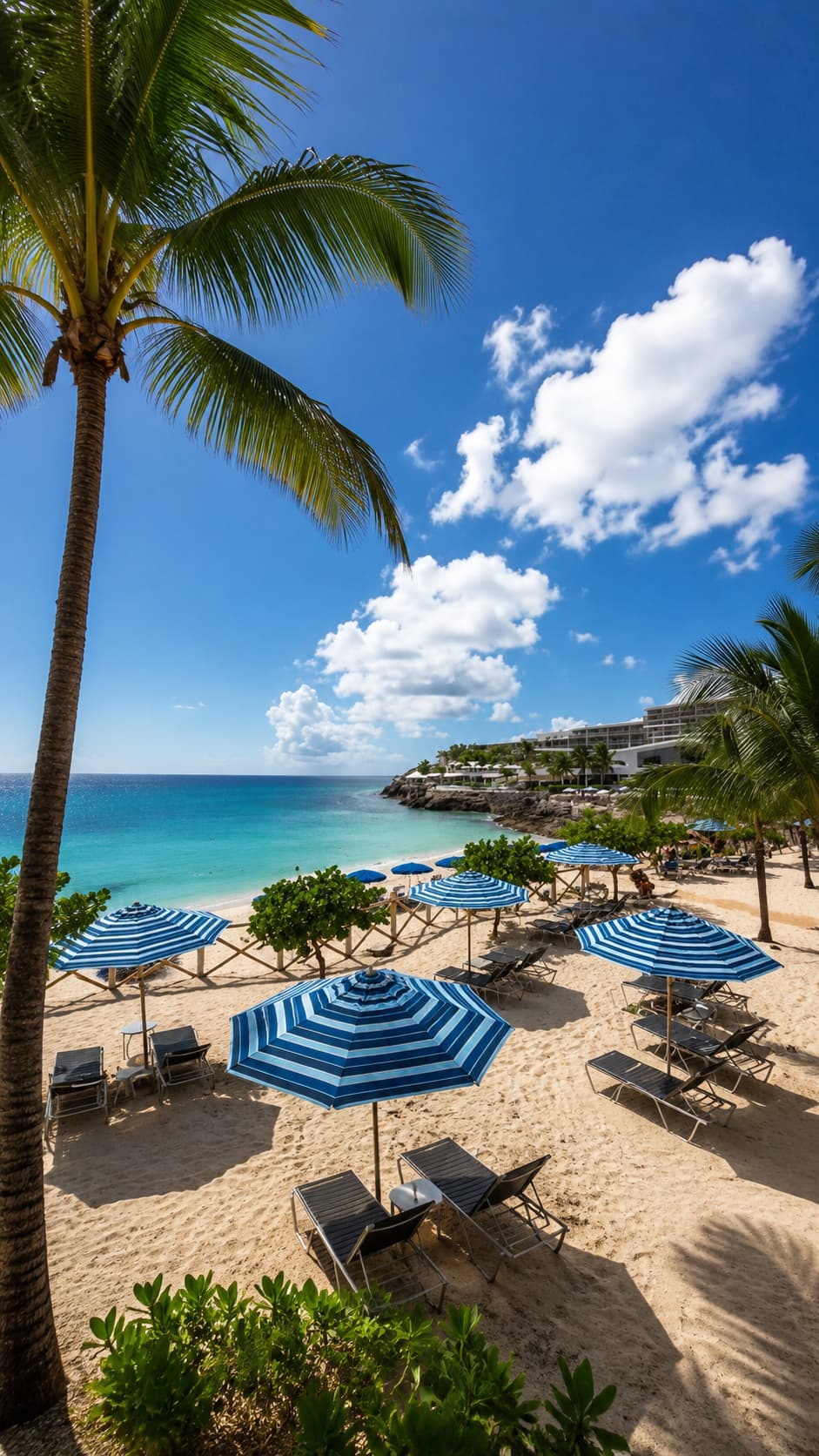 A resort beach with striped umbrellas and palm trees under a bright Caribbean sky