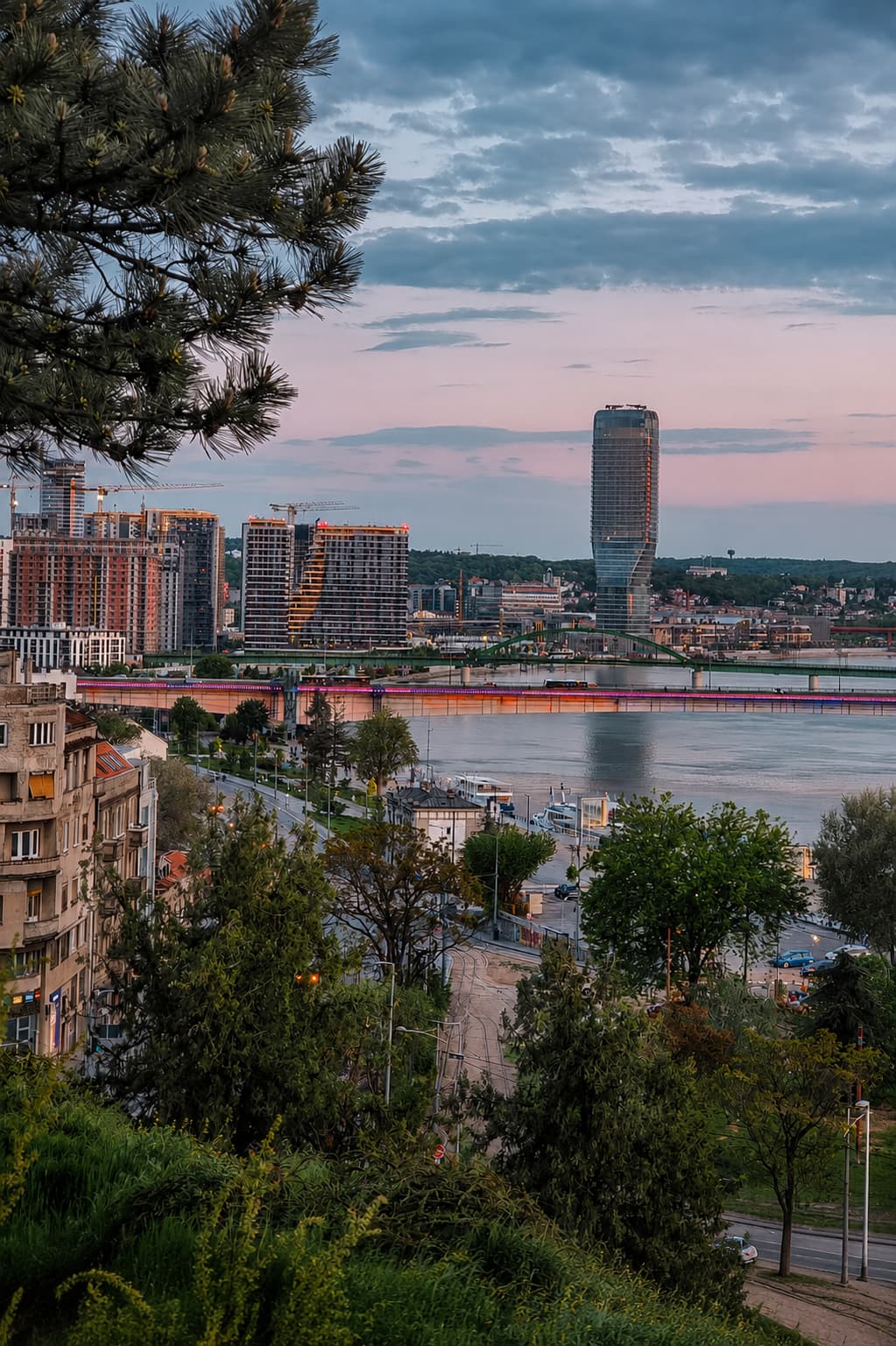 Belgrade skyline at dusk with the Sava river, illuminated bridge, and modern Ušće tower