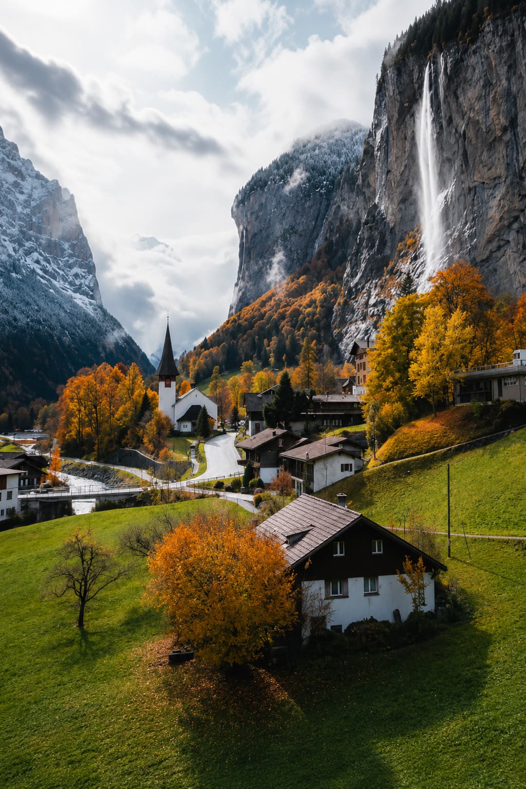 Lauterbrunnen valley in the Swiss Alps in October, Swiss chalet village with a waterfall cascading down cliff faces and golden autumn trees covering the hillsides