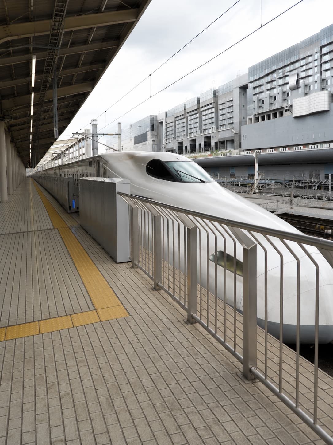 japan solo travel - Shinkansen bullet train at a Japanese station platform — the sleek white nose of the N700 series waiting to depart