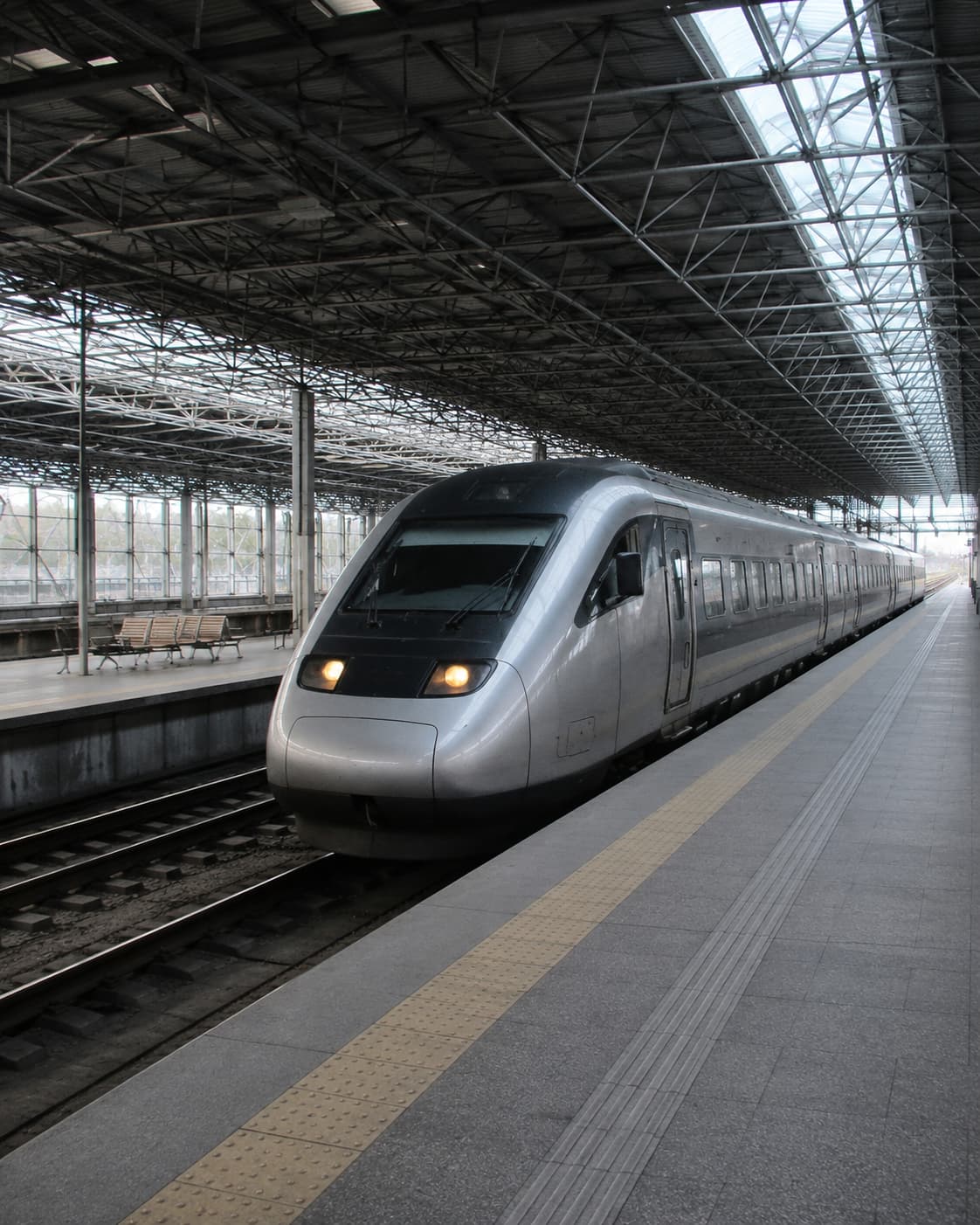 A high-speed train at a station platform under a glass and steel canopy — the Alfa Pendular connects Lisbon and Porto in around three hours