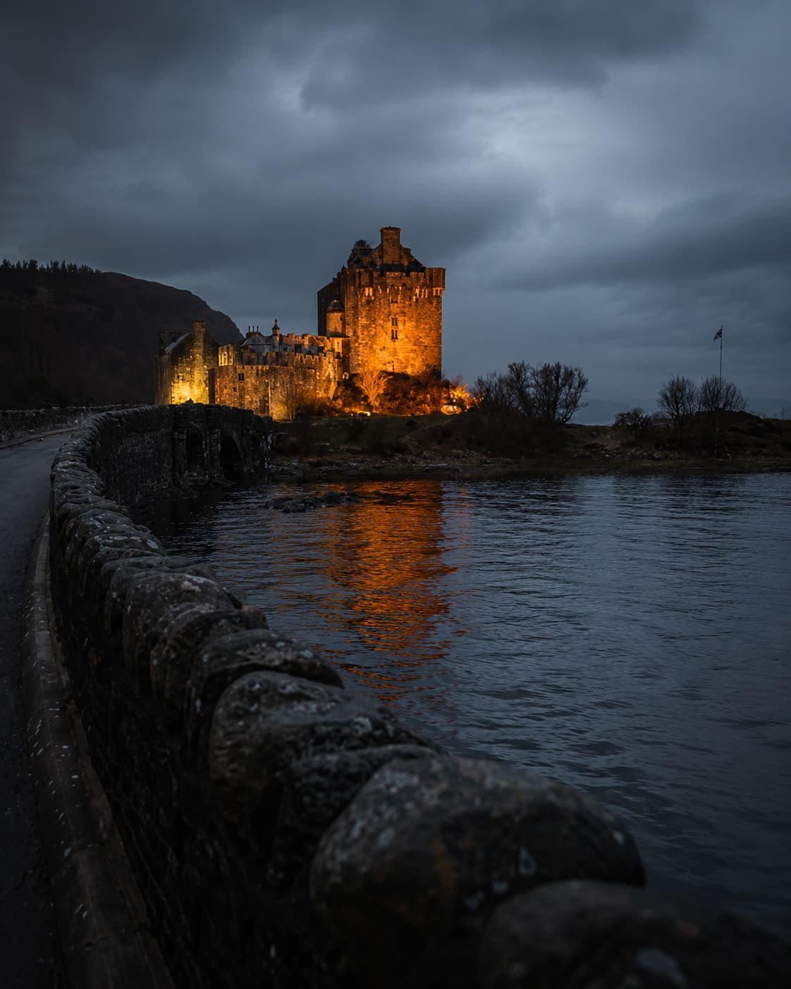 Eilean Donan Castle illuminated at dusk and reflected in the loch — Scotland's most cinematic Highland castle, close to the Outlander filming region