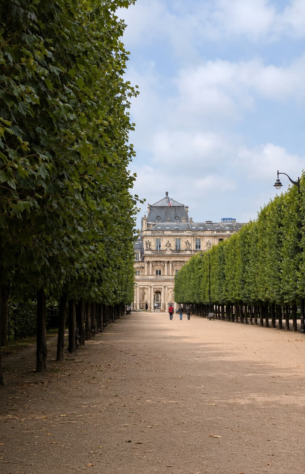 Palais Royal gardens in Paris, a gravel path lined with trimmed trees leading toward the palace façade