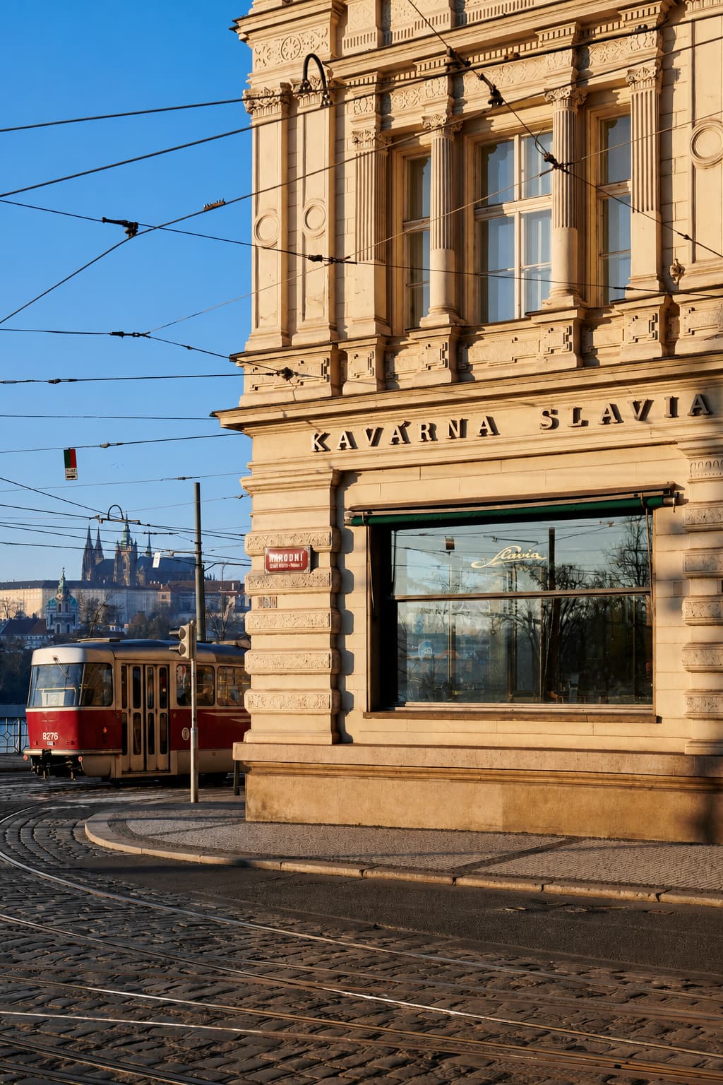 Kavárna Slavia exterior on Smetanovo nábřeží — one of the most famous historic cafés in Prague, with a red tram passing and Prague Castle in the background
