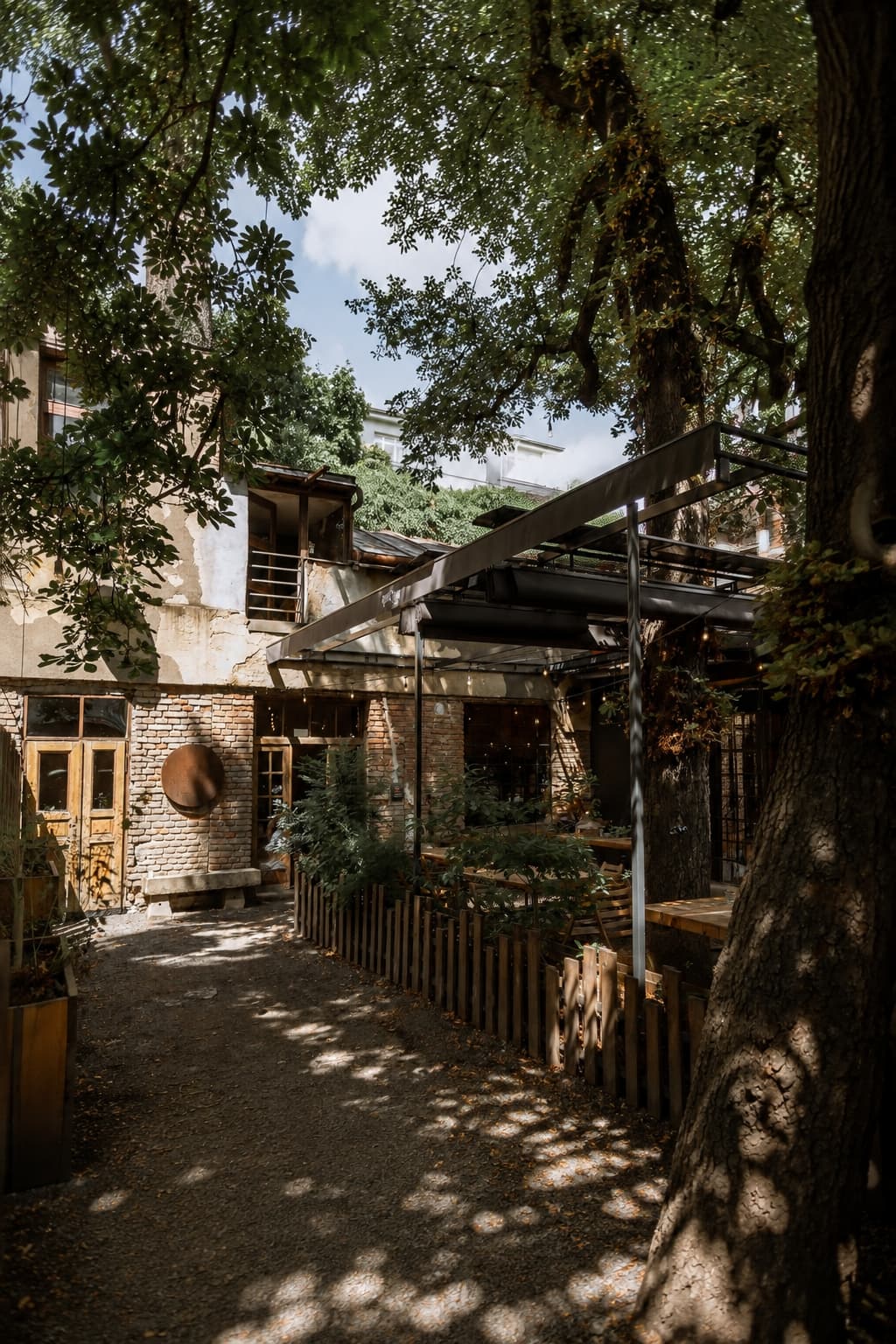 Courtyard café in Prague with trees, brick walls, and outdoor seating — neighbourhood café in Žižkov or Vinohrady