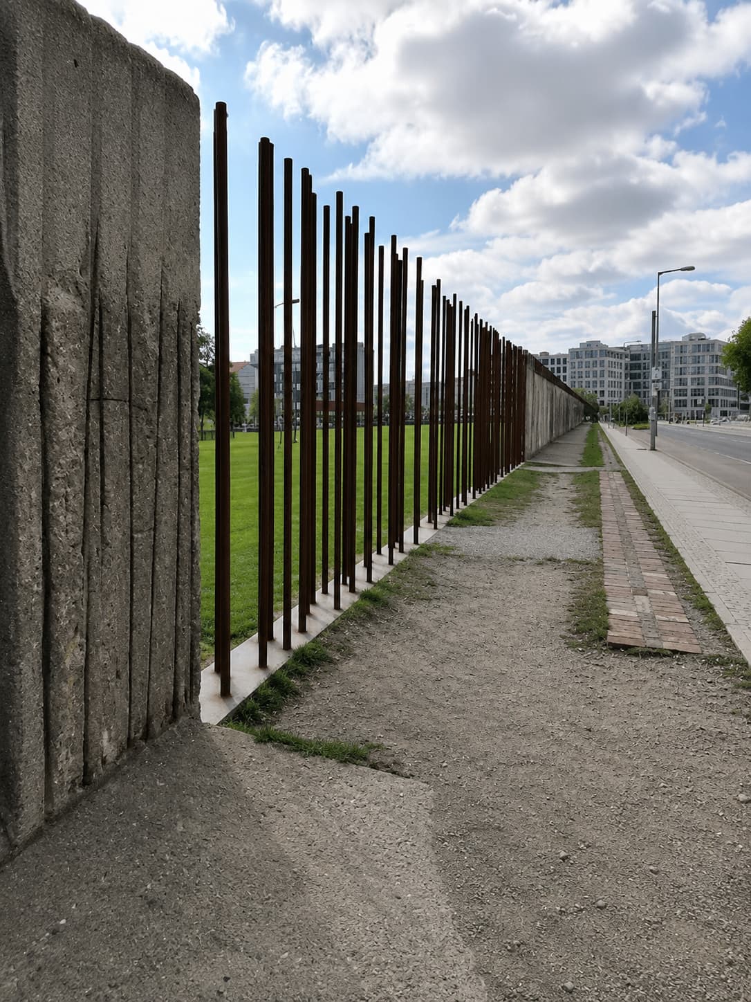 Solo traveler's view along the Berlin Wall memorial — steel rods and concrete stretching into the distance