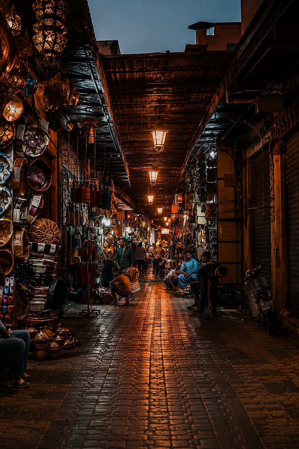Marrakech souk alley at night with brass lanterns, market stalls, and shopkeepers — the evening atmosphere Morocco travel tips rarely capture