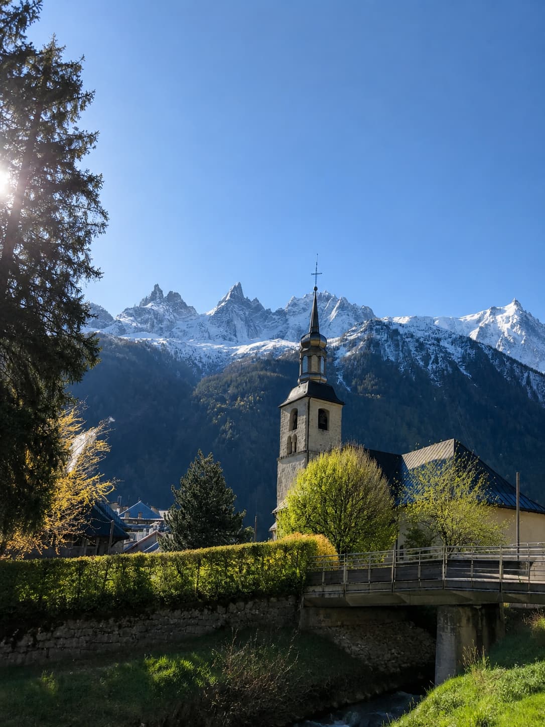 Chamonix church steeple in the French Alps in October with the snow-covered Aiguilles du Midi and Mont Blanc massif rising behind in clear autumn light