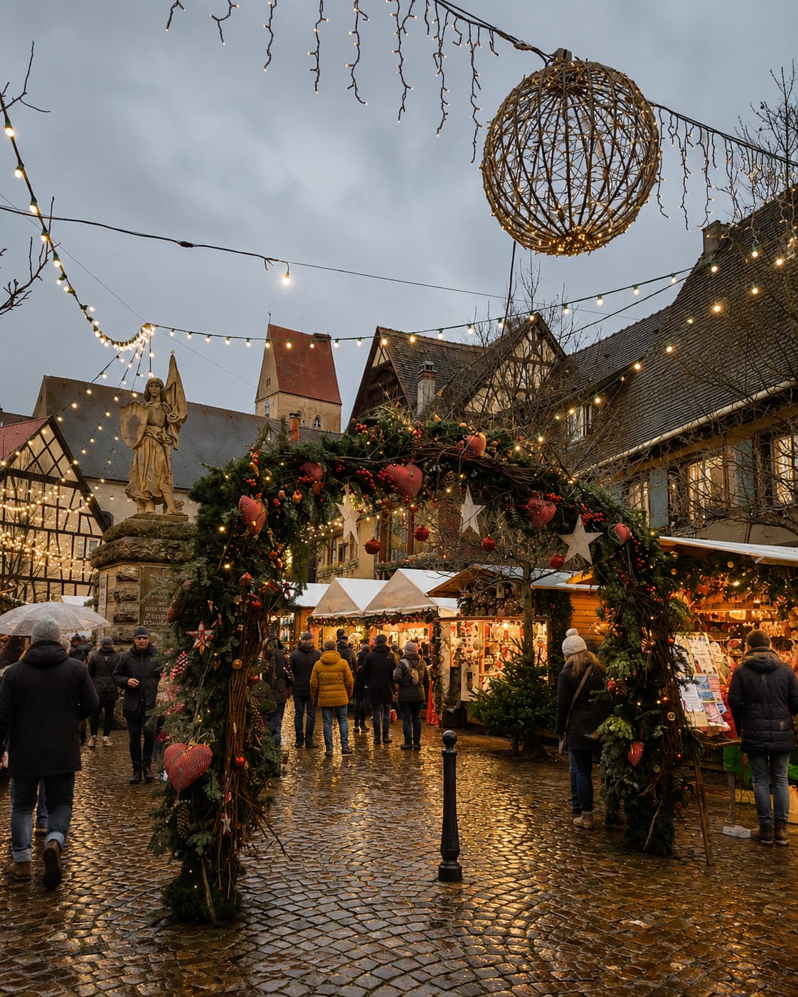 Alsace village Christmas market with floral garland archway, half-timbered buildings and cobblestone street in rain