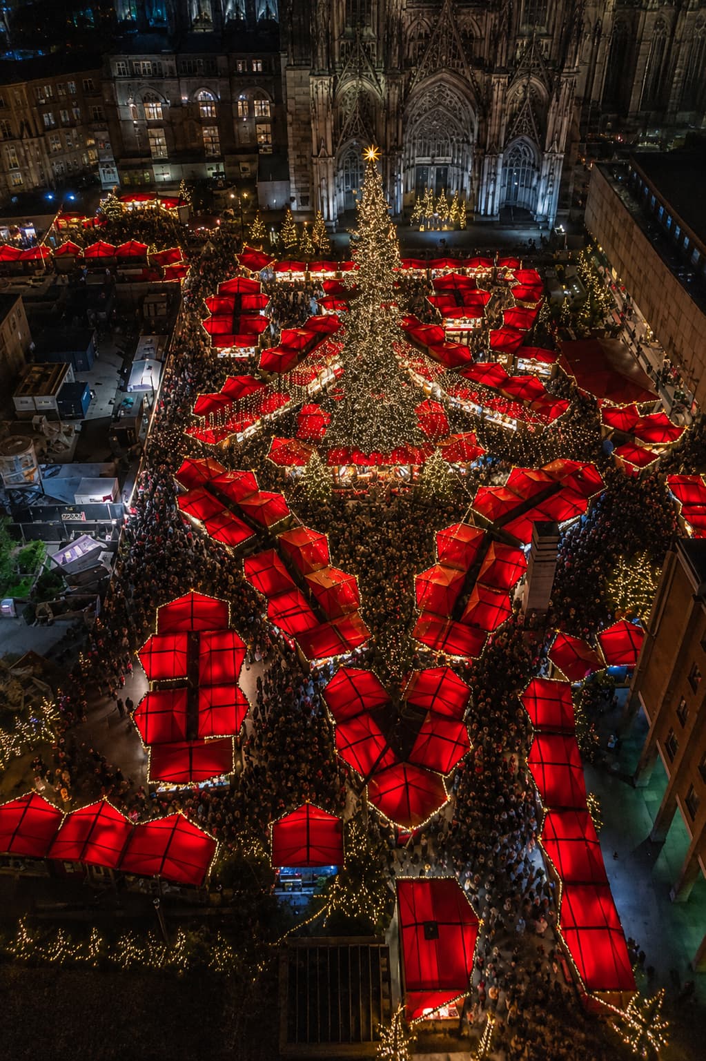 Cologne Cathedral Christmas market aerial at night, red star-shaped tents and massive Christmas tree, Kölner Dom behind