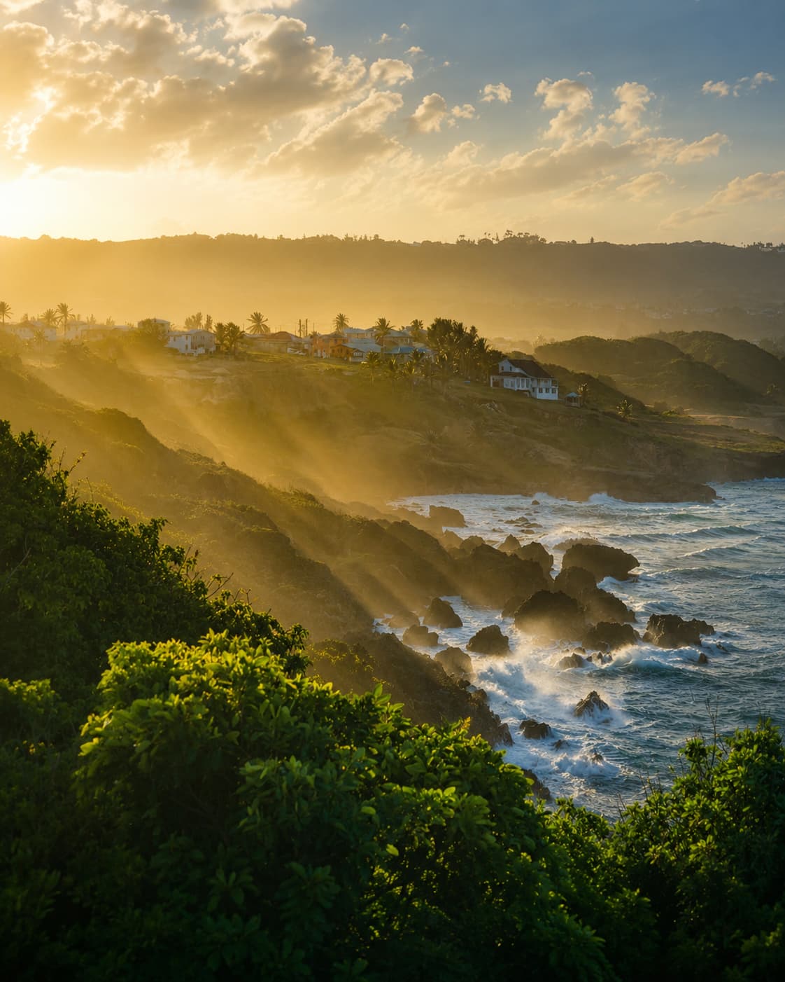 Barbados coastline at golden sunset with sun rays breaking through clouds over the rocky Atlantic shore and tropical vegetation — a winter birthday trip idea