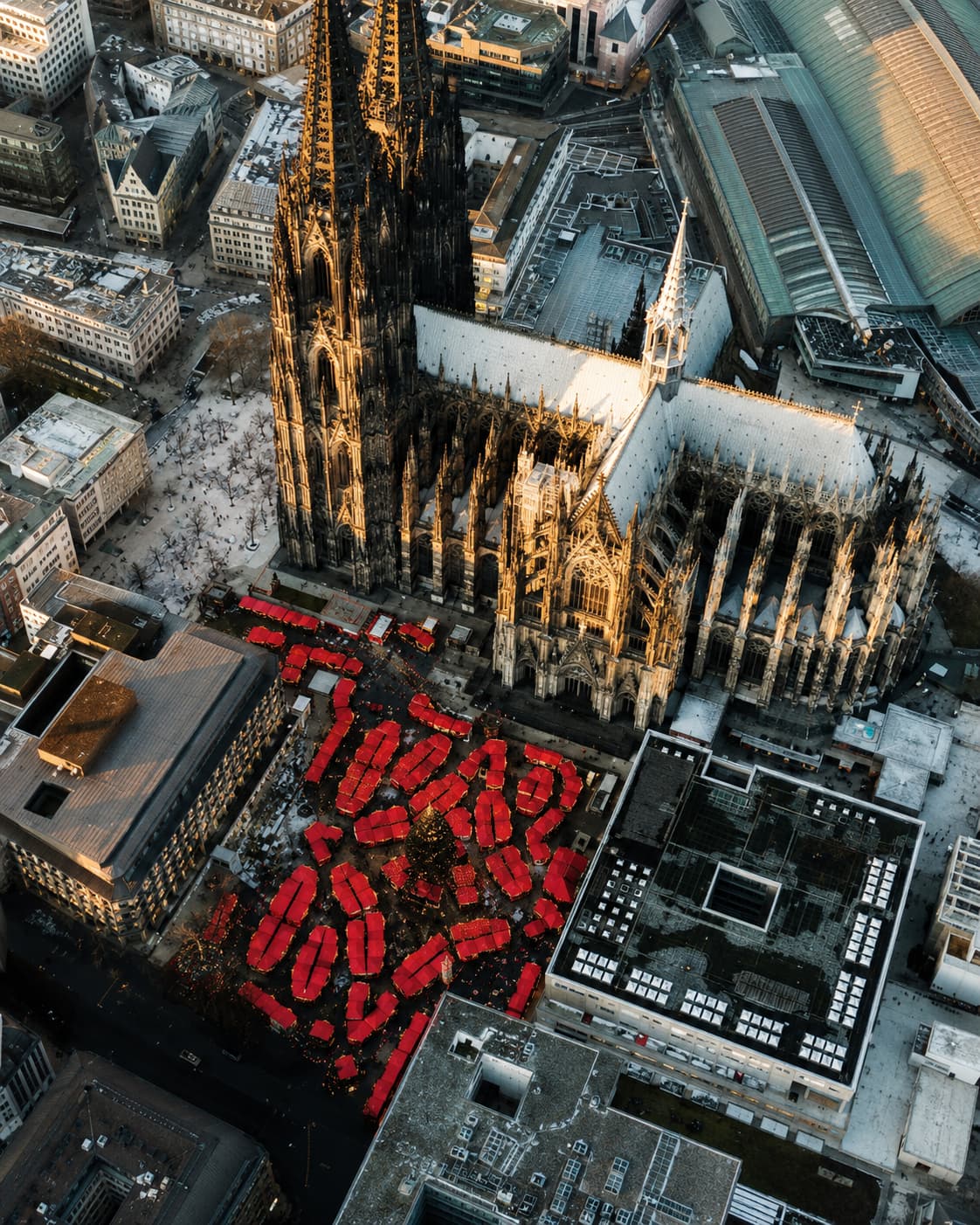 Cologne Cathedral Christmas market aerial drone view with red stalls beside the Gothic Dom spires — European Christmas market opening date 23 November 2026