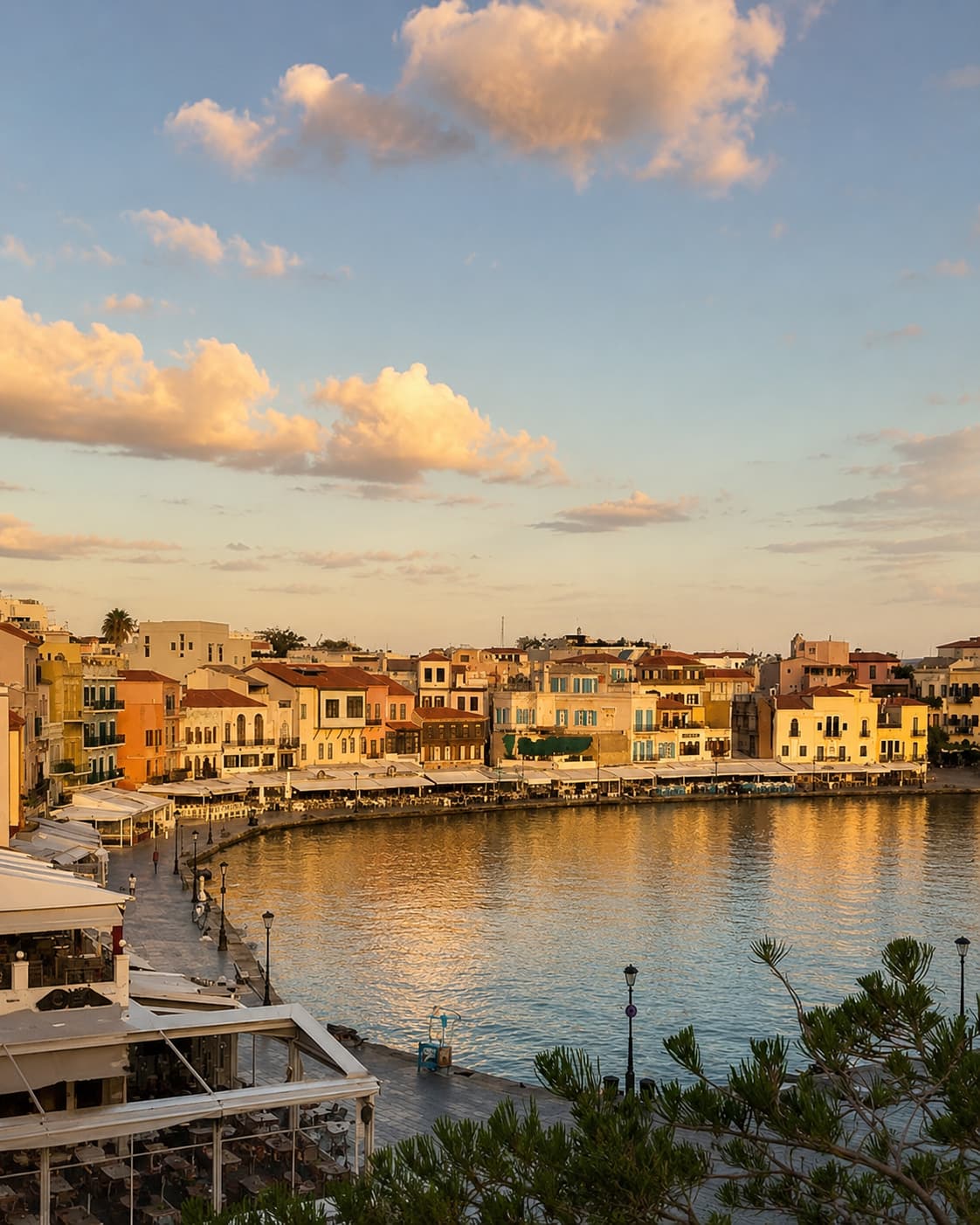 Chania old Venetian harbour at golden sunset, colourful waterfront buildings reflected in still water, Crete in October light