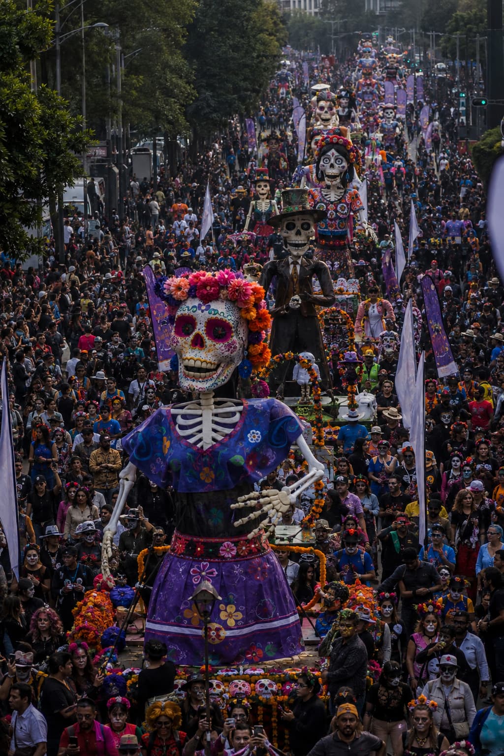 Aerial view of the Day of the Dead parade Mexico City procession filling Paseo de la Reforma, giant Catrina floats visible