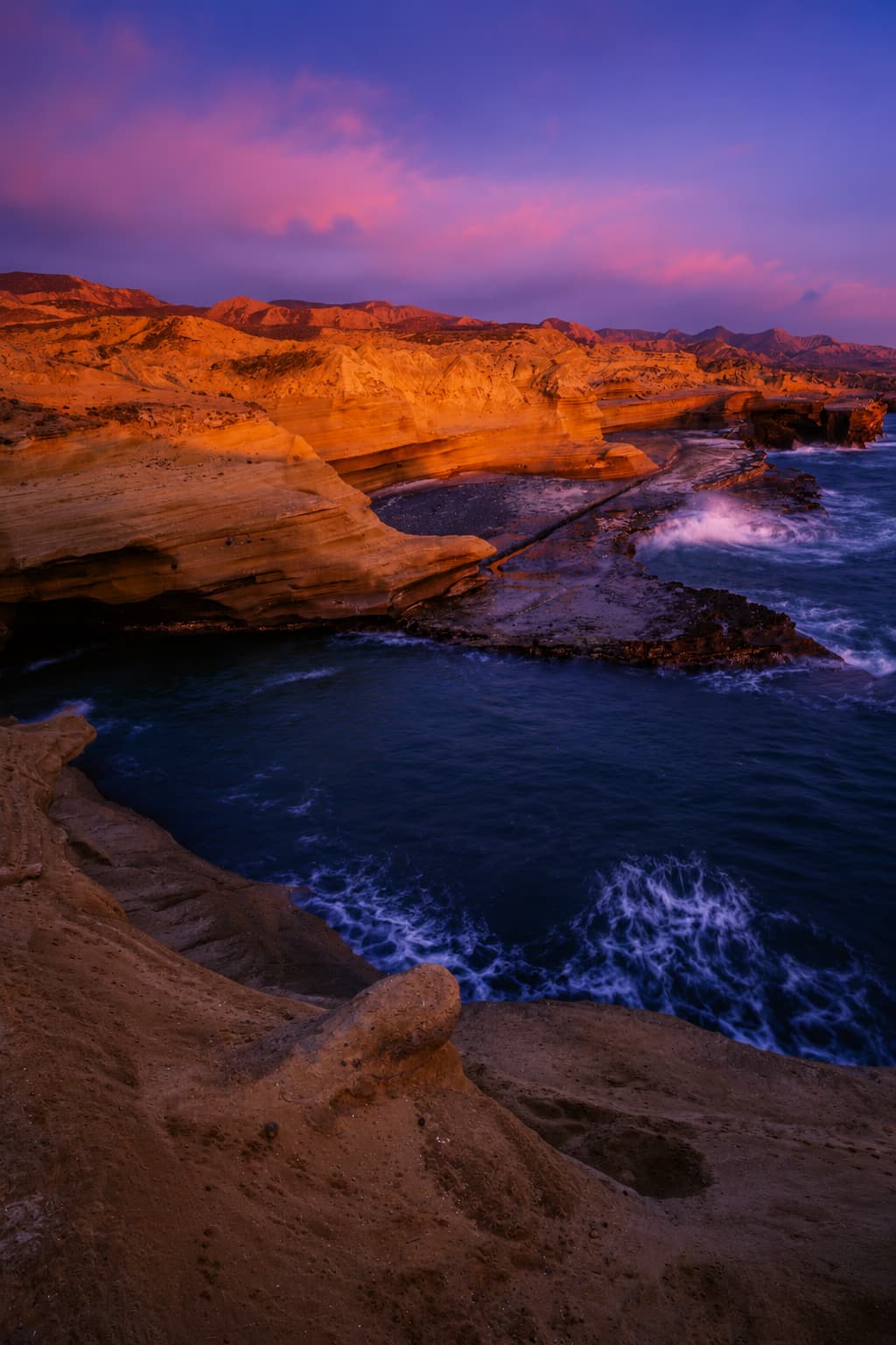Volcanic sandstone cliffs and dark Atlantic sea at dramatic purple sunset in the Canary Islands — warm December destination without a long-haul flight