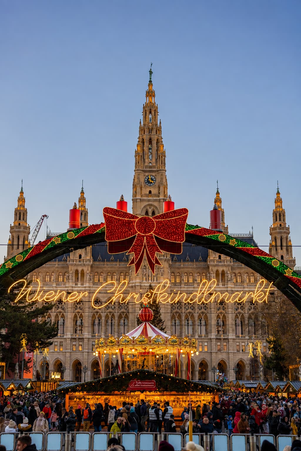 The Vienna Christkindlmarkt sign glowing in front of the illuminated Rathaus at dusk — Vienna's Christmas market is the strongest reason to go to Europe in November