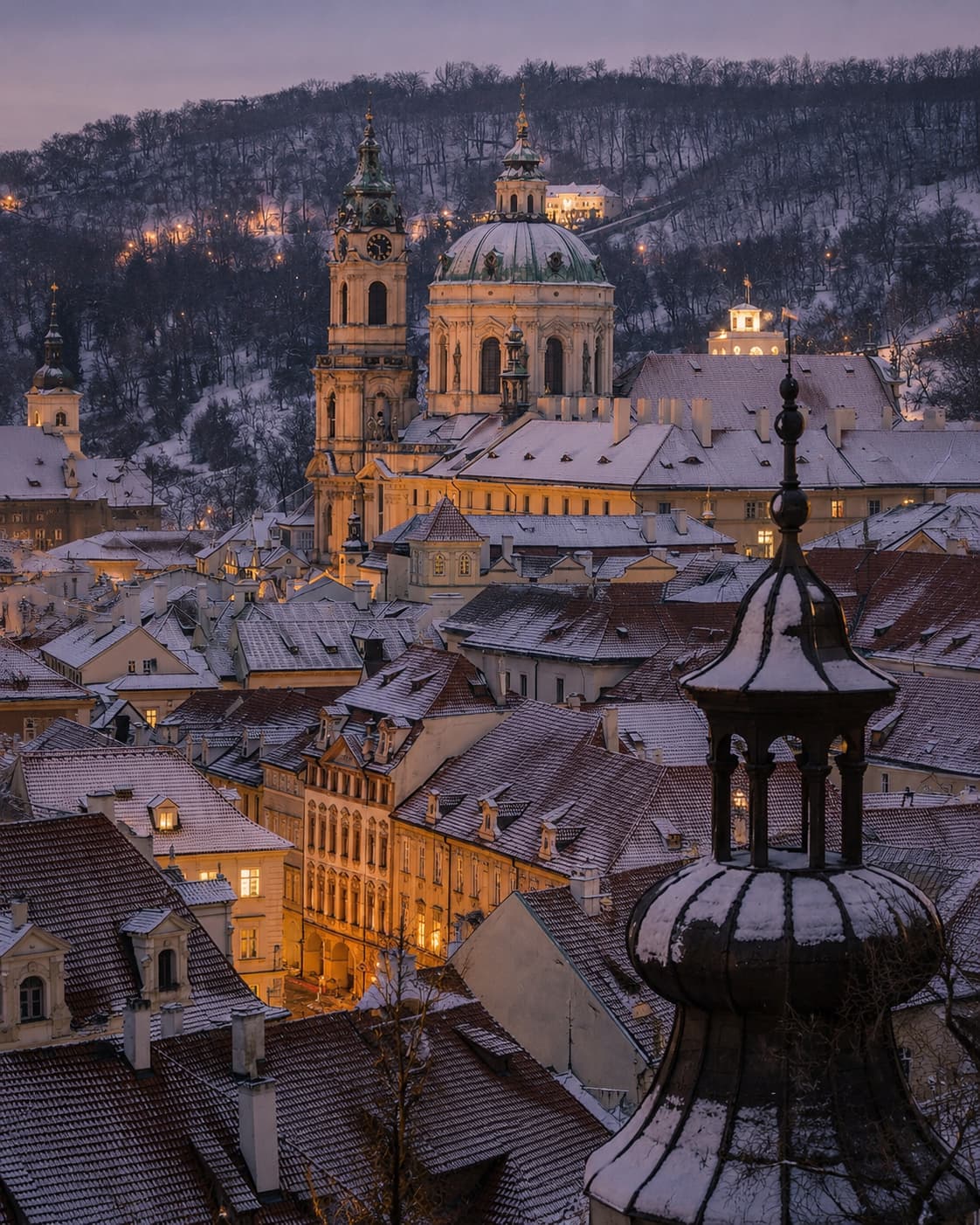 Snow-covered rooftops and the dome of St Nicholas Church glowing at blue hour in Prague in winter — Prague is one of the best places to go in Europe in November and stays open into January