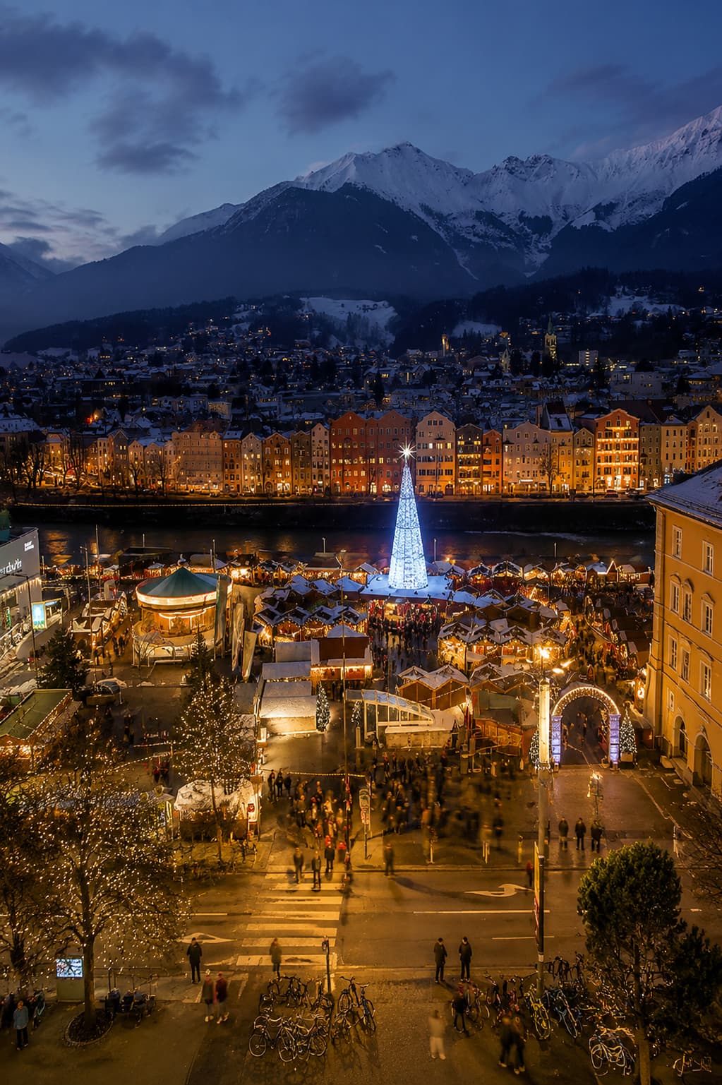 austria christmas markets — Innsbruck Christkindlmarkt at night with snow-capped Alps rising directly above the city