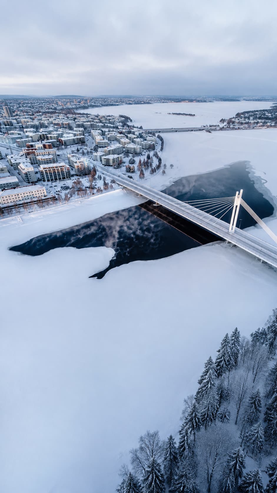 Aerial view of Rovaniemi in winter — Lumberjack's Candle Bridge over the frozen Kemijoki river, snow-covered city, the most accessible place to stay in Lapland