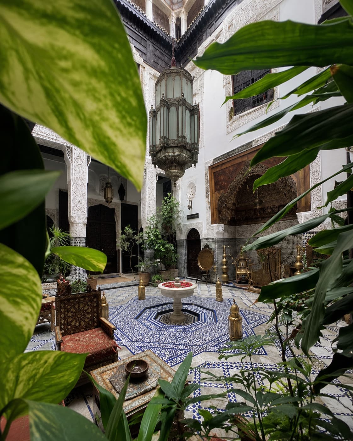 Traditional riad courtyard in Fes with zellige tile floor and brass Moroccan lantern — Morocco travel in any season