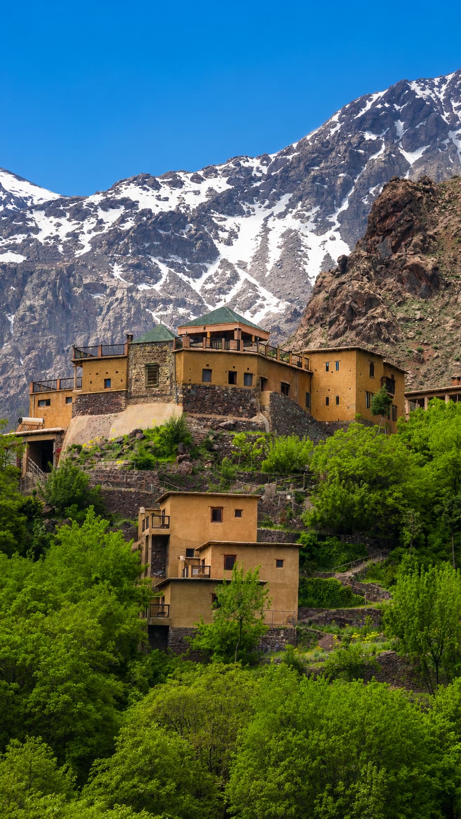 High Atlas Mountains in spring with snow-capped peaks above a Berber village — Morocco weather varies dramatically by region