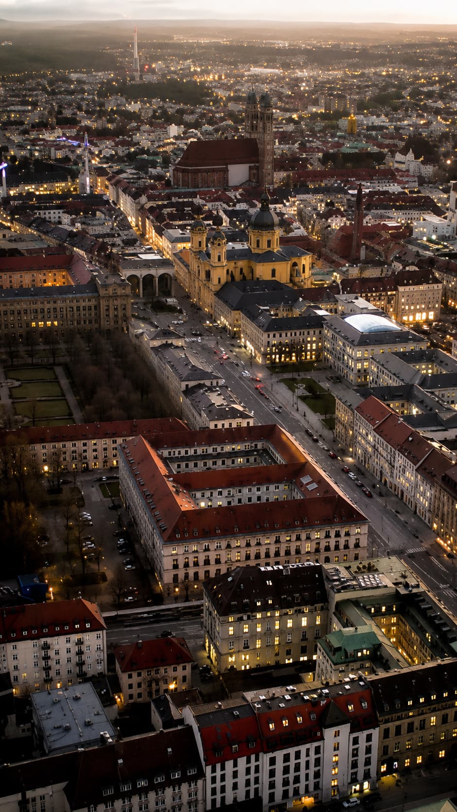 Aerial view of Munich city at dusk with the Theatinerkirche and Odeonsplatz illuminated by warm city lights