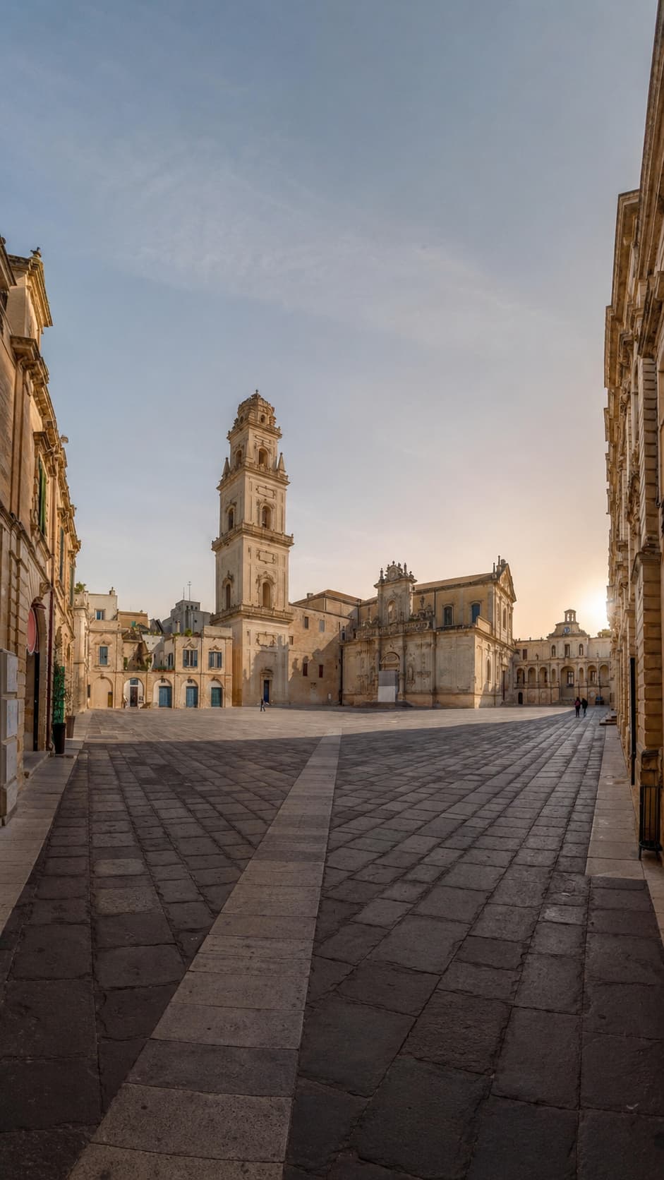 Piazza del Duomo in Lecce at dawn, the Baroque cathedral and bell tower rising over an empty square in pale golden Lecce stone