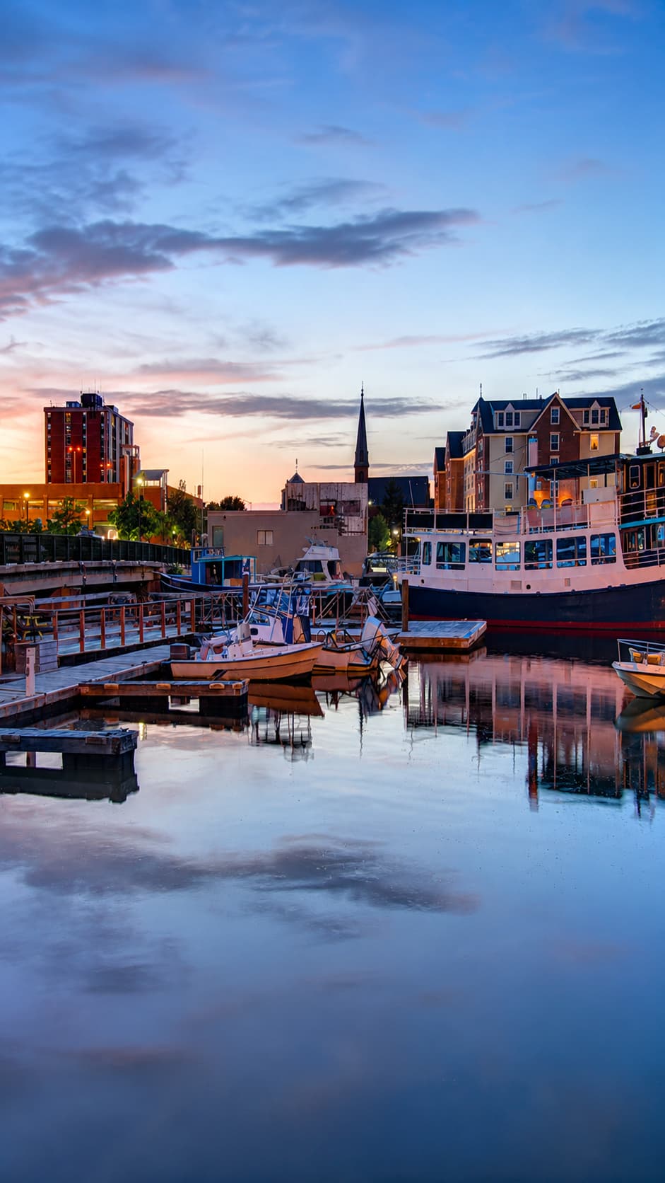 Salem harbour at sunset — boats moored at the waterfront, city skyline reflected in calm water