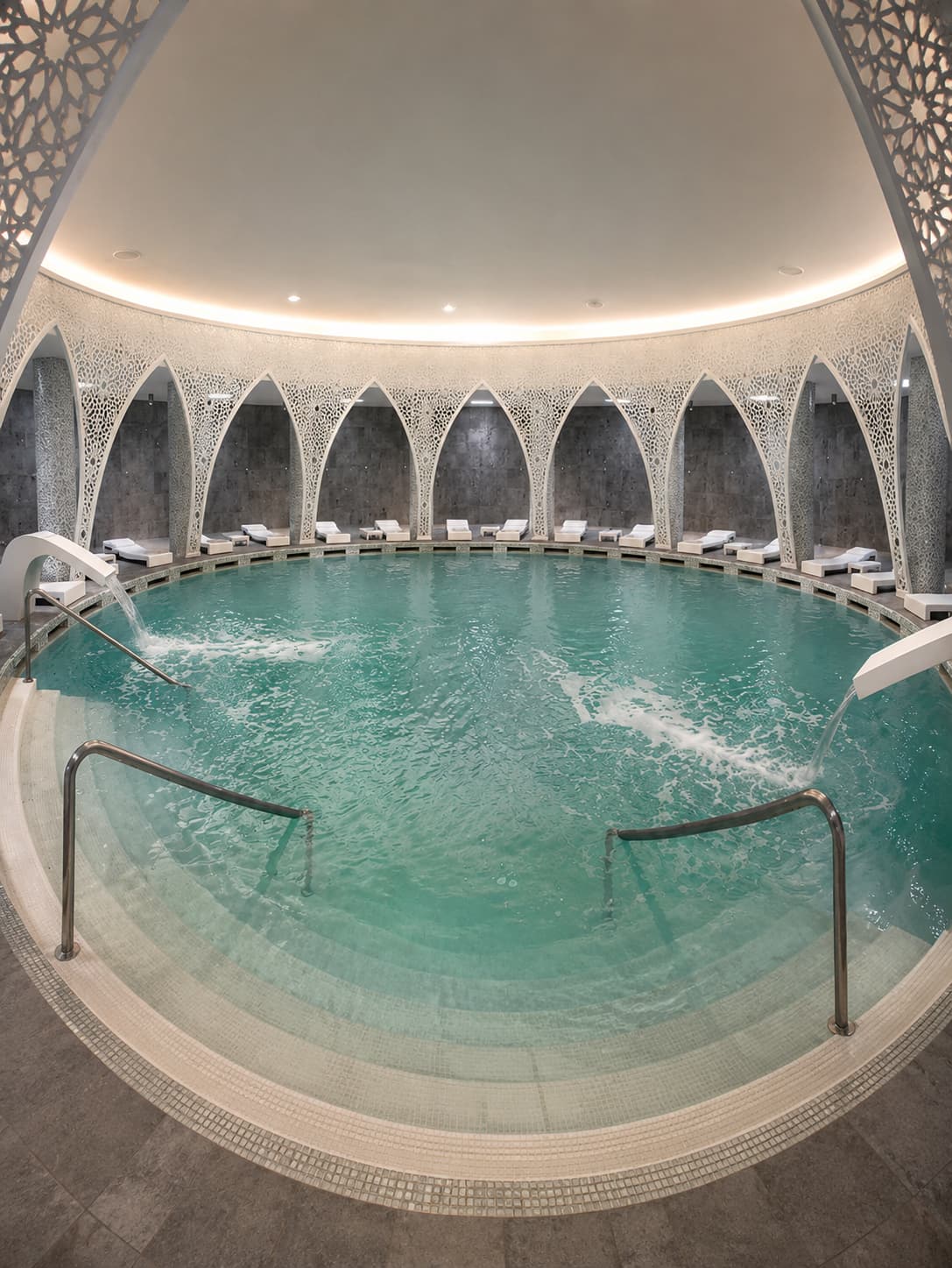Modern thermal pool with Islamic-arch lattice screens and curved interior at a European spa town thermal facility, showing the contemporary wellness design found at renovated spa destinations across Europe