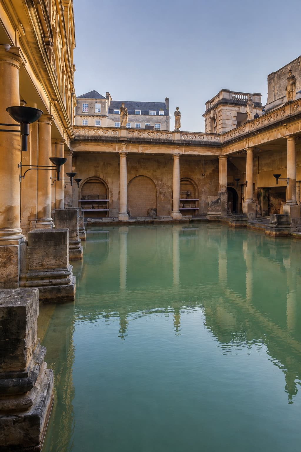 The Roman Baths in Bath, England — a UNESCO Great Spa Town of Europe — with green thermal water, Roman columns, and Georgian buildings rising above the ancient bathing pool